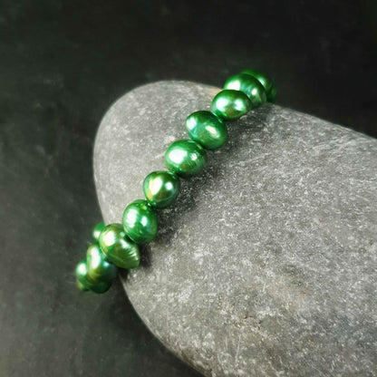 Groen zoetwaterparel armband liggend tegen steen | Green Pearl