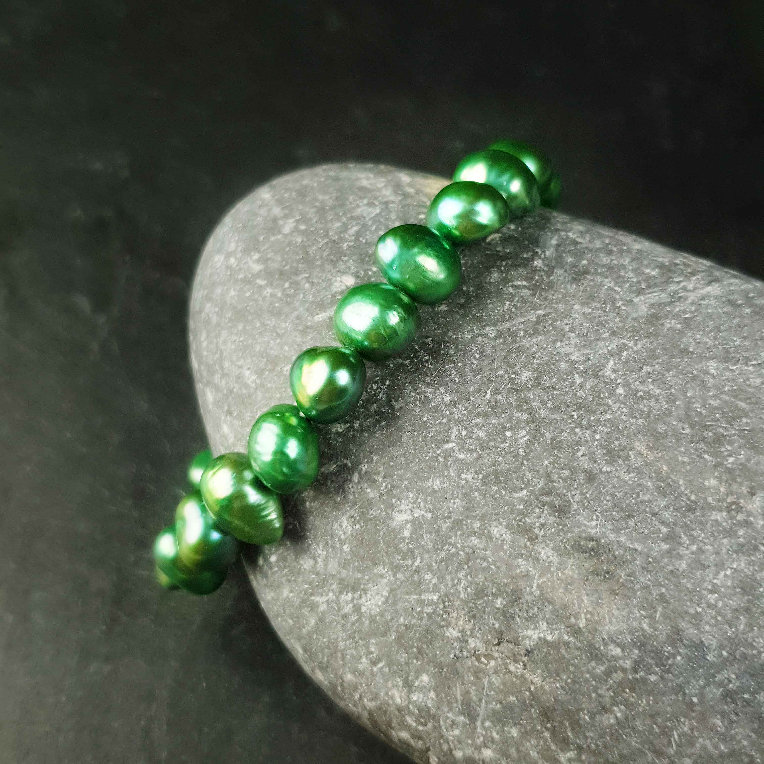 Groen zoetwaterparel armband liggend tegen steen | Green Pearl