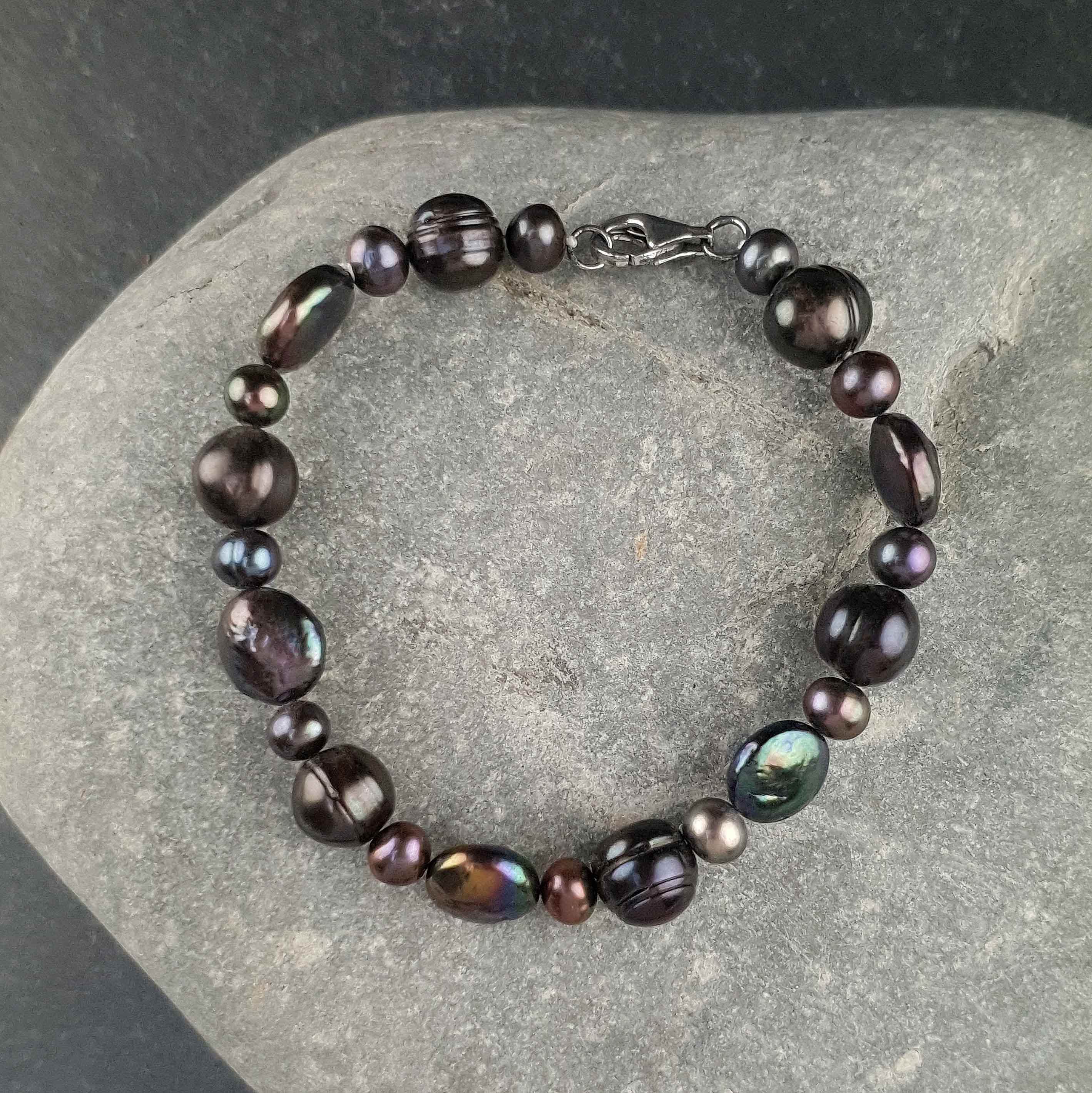Zoetwater parel armband met groen zwarte parels en sterling zilver (925) liggend op kei | Peacoin
