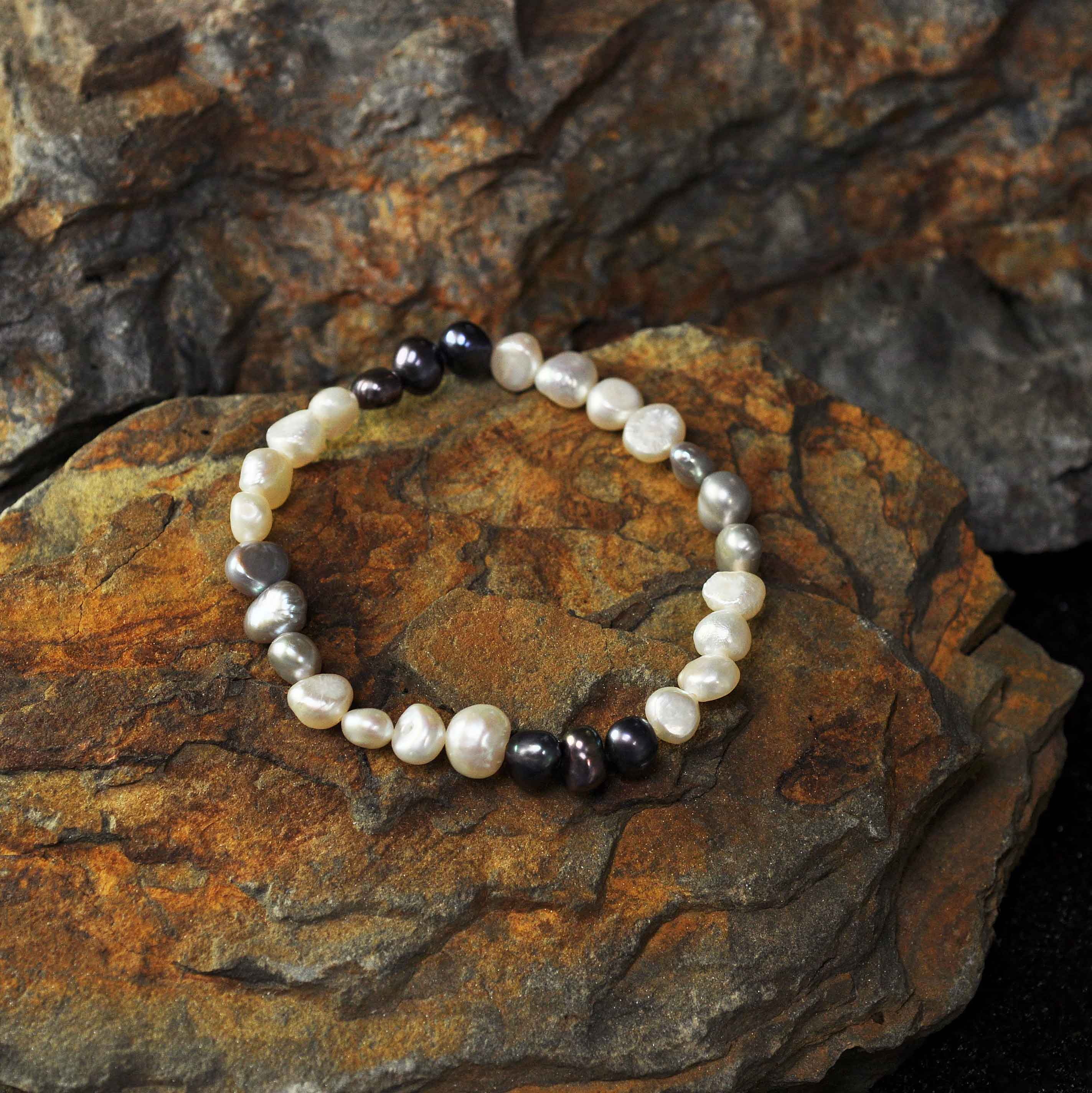 Zoetwater parel armband met witte, grijze en blauwe parels, elastisch, liggend op steen | Pearl Trio White Grey Blue