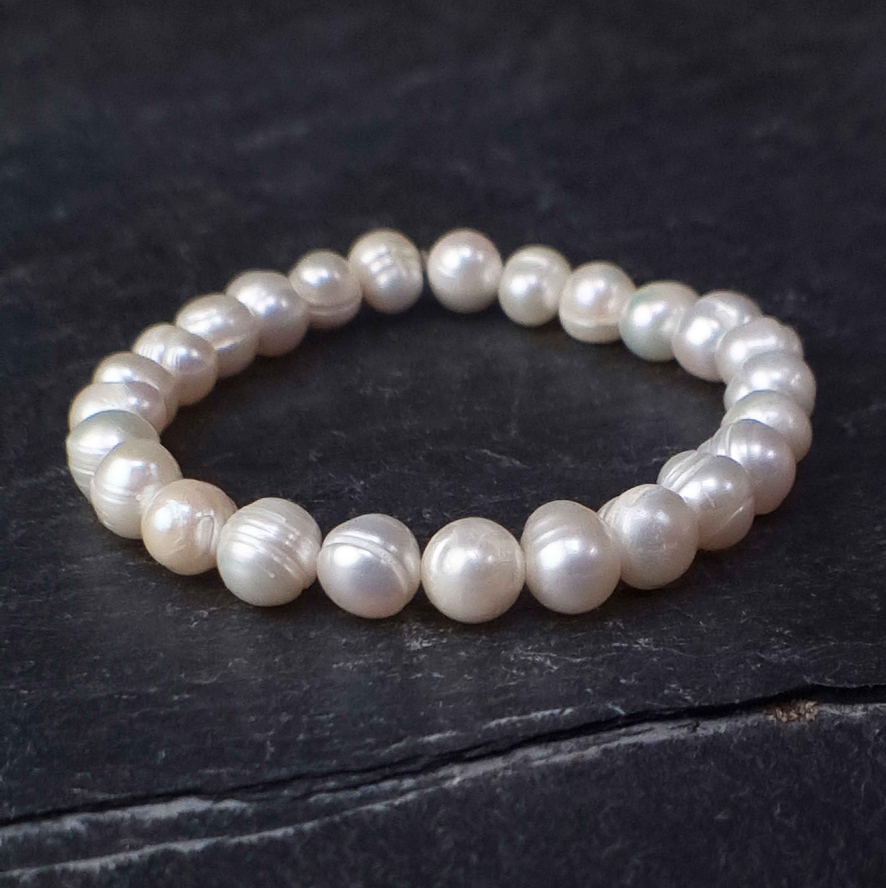 Wit elastisch zoetwater parel armband liggend op leisteen | Round White