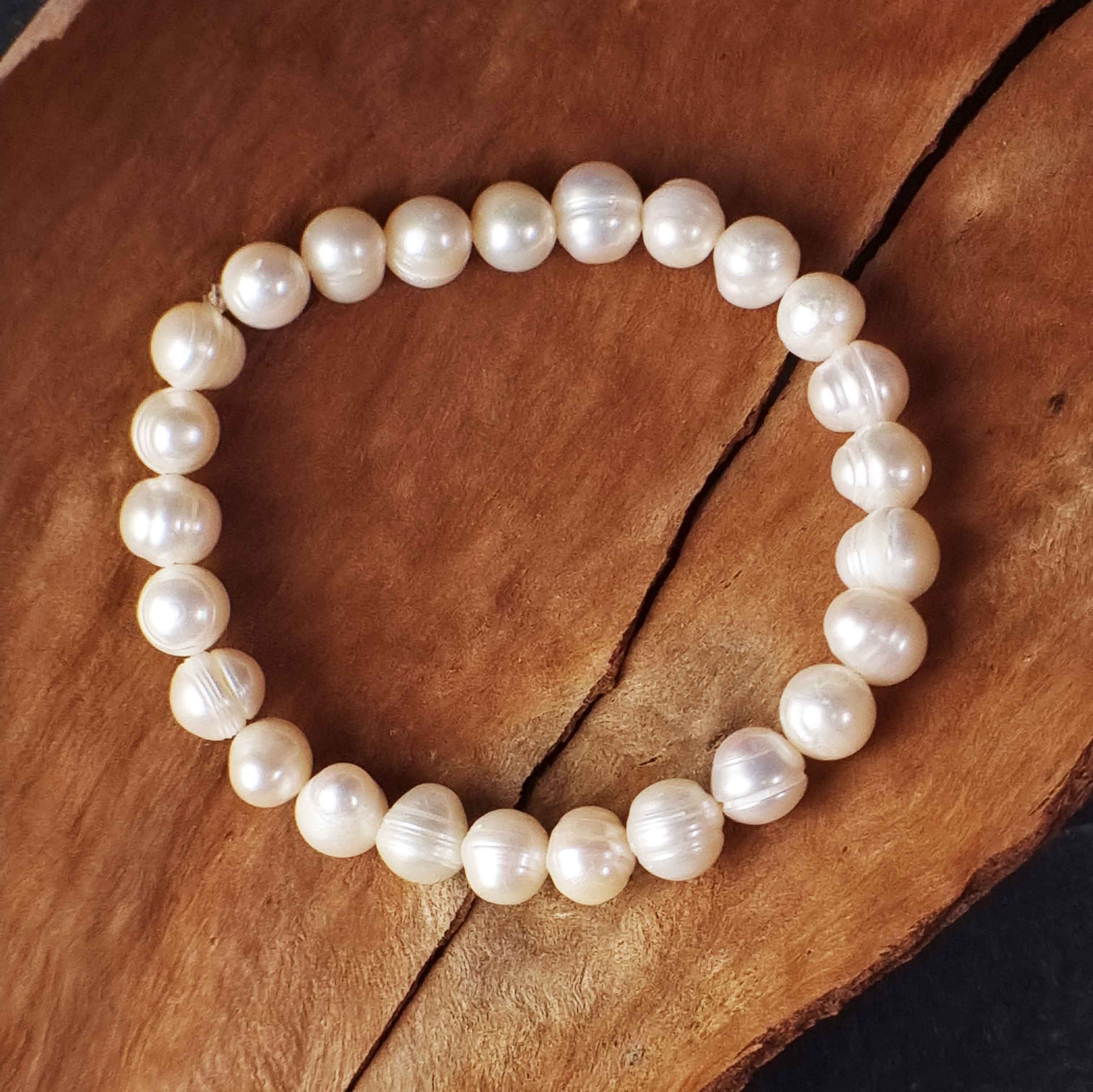 Wit elastisch zoetwater parel armband liggend op schors | Round White