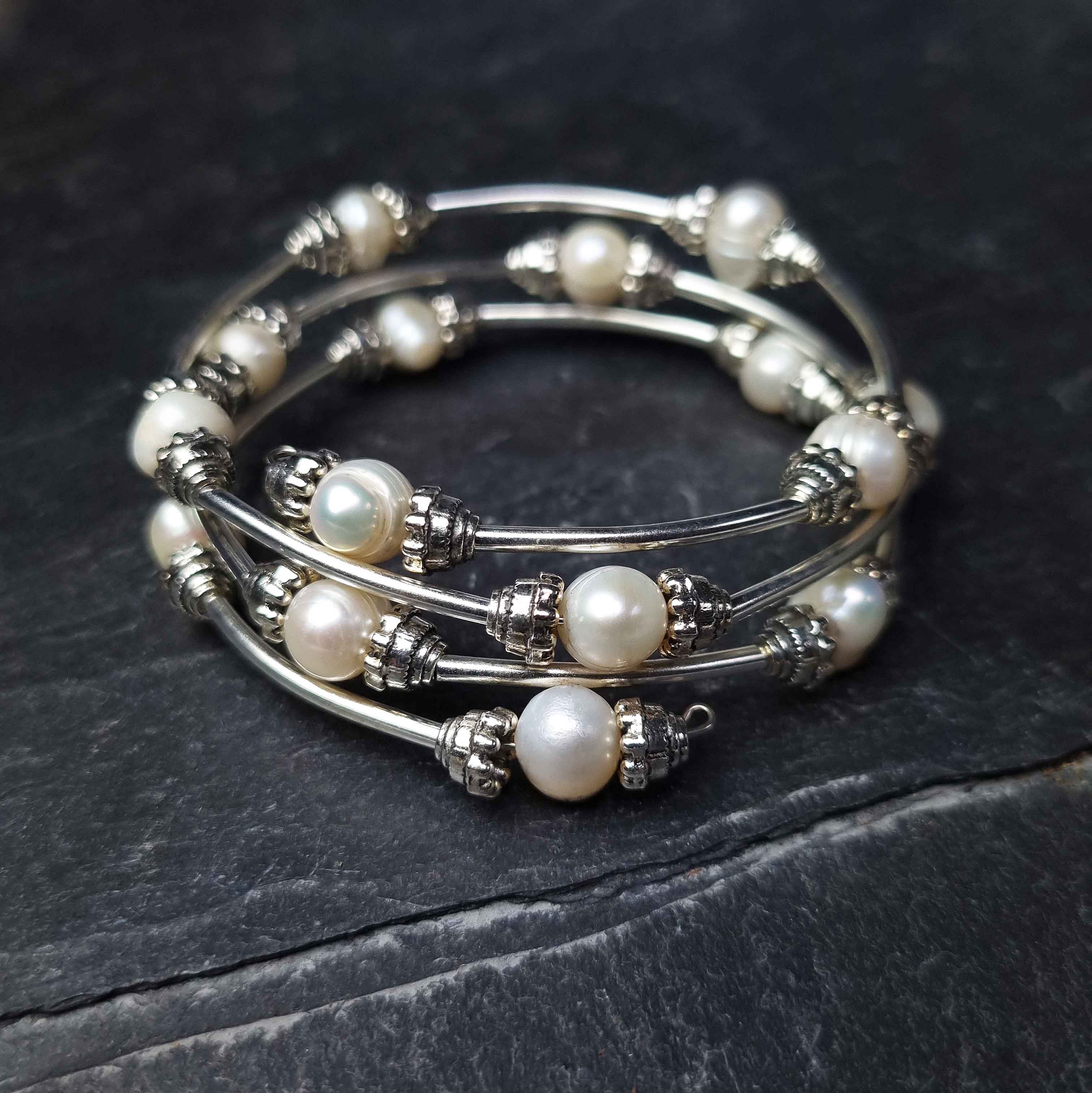 Wit zoetwater parel wikkelarmband liggend op leisteen | Three Loops White Pearlarmband