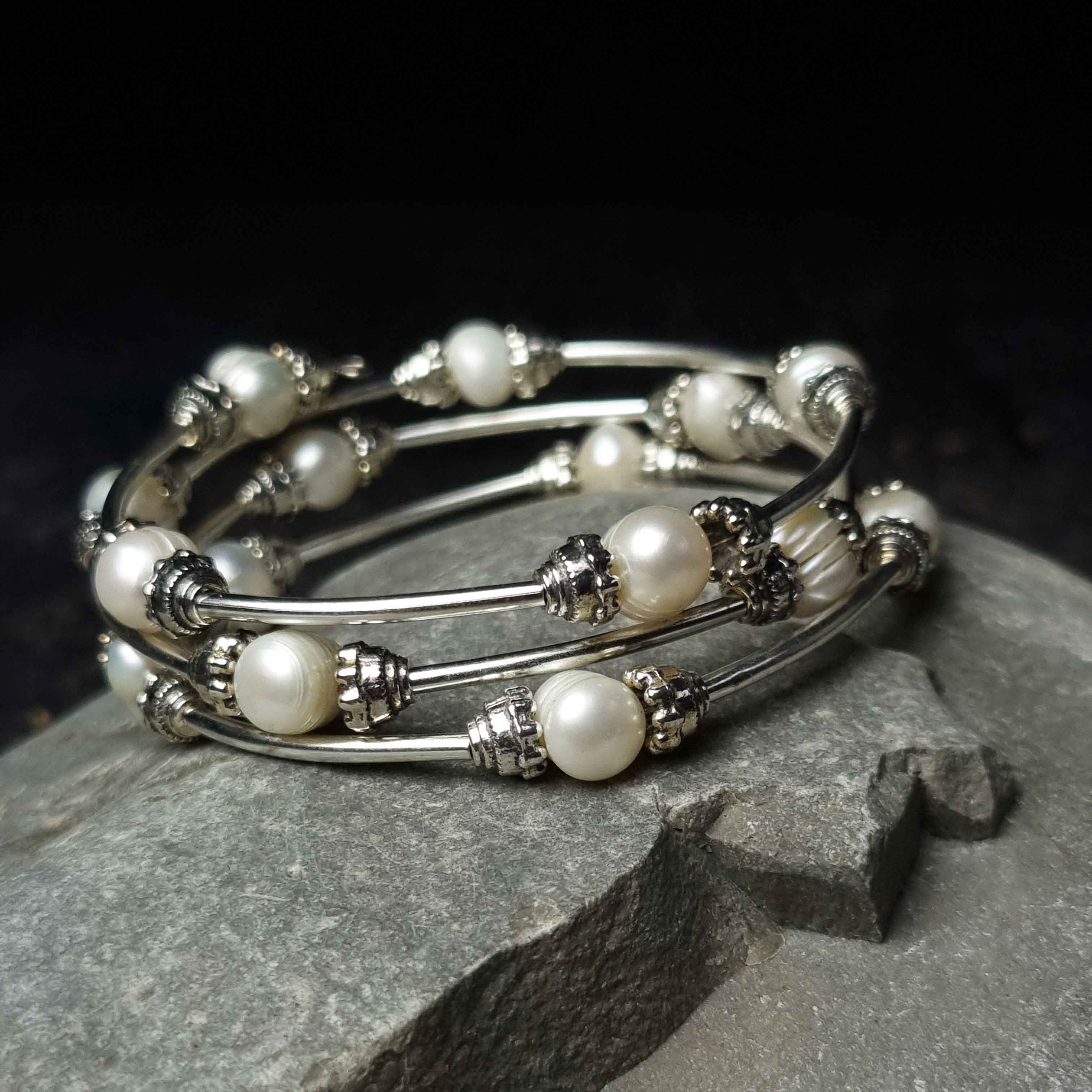 Wit zoetwater parel wikkelarmband liggend op kei | Three Loops White Pearlarmband