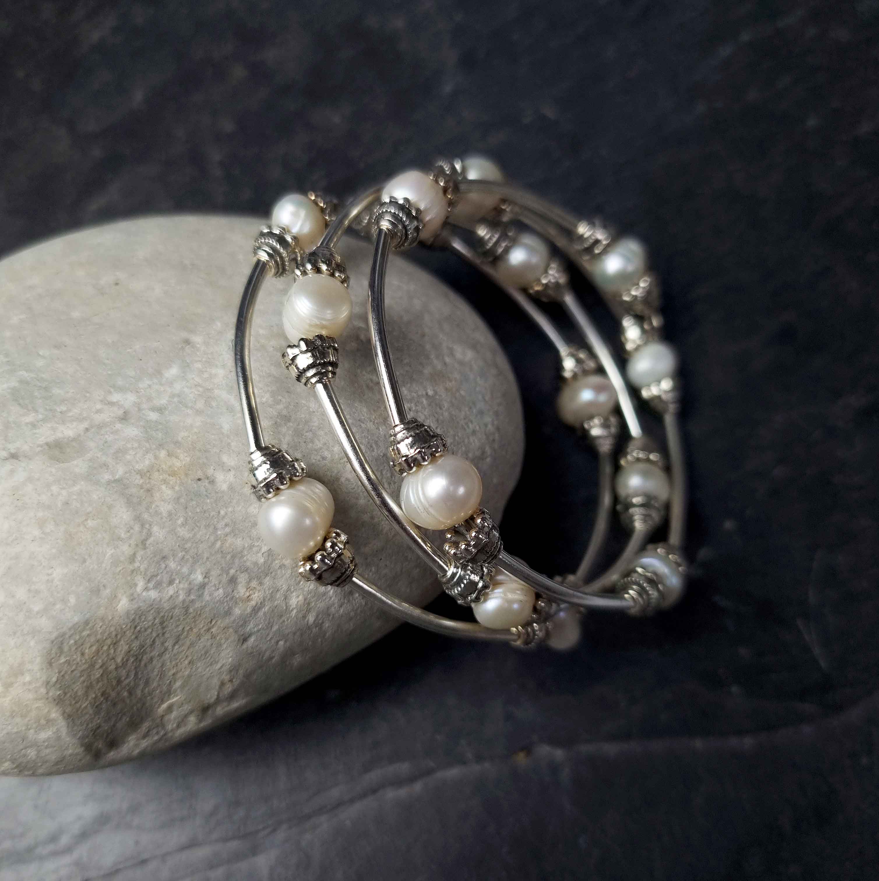 Wit zoetwater parel wikkelarmband liggend tegen kei | Three Loops White Pearlarmband