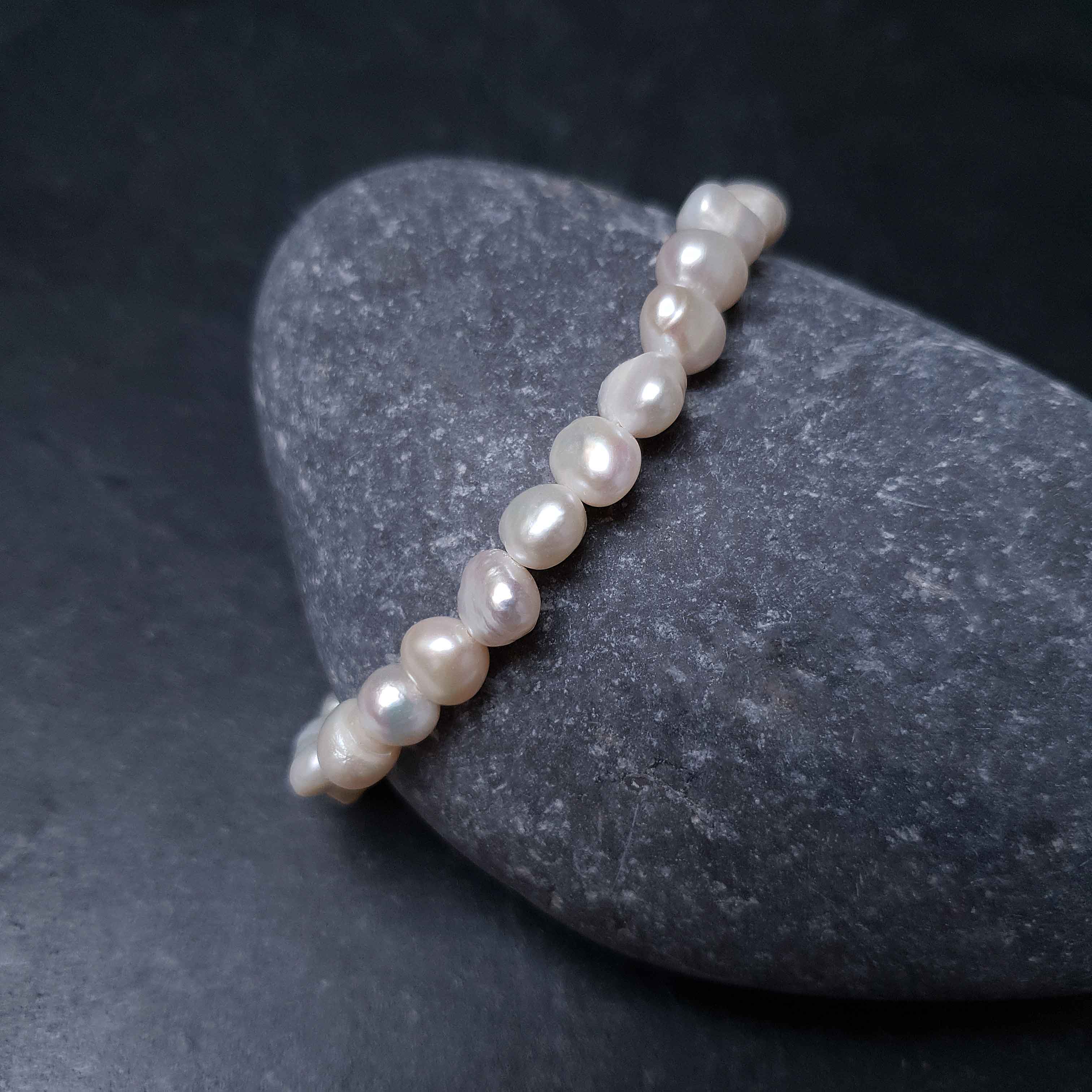 Wit zoetwater parel armband liggend op kei | Weaca