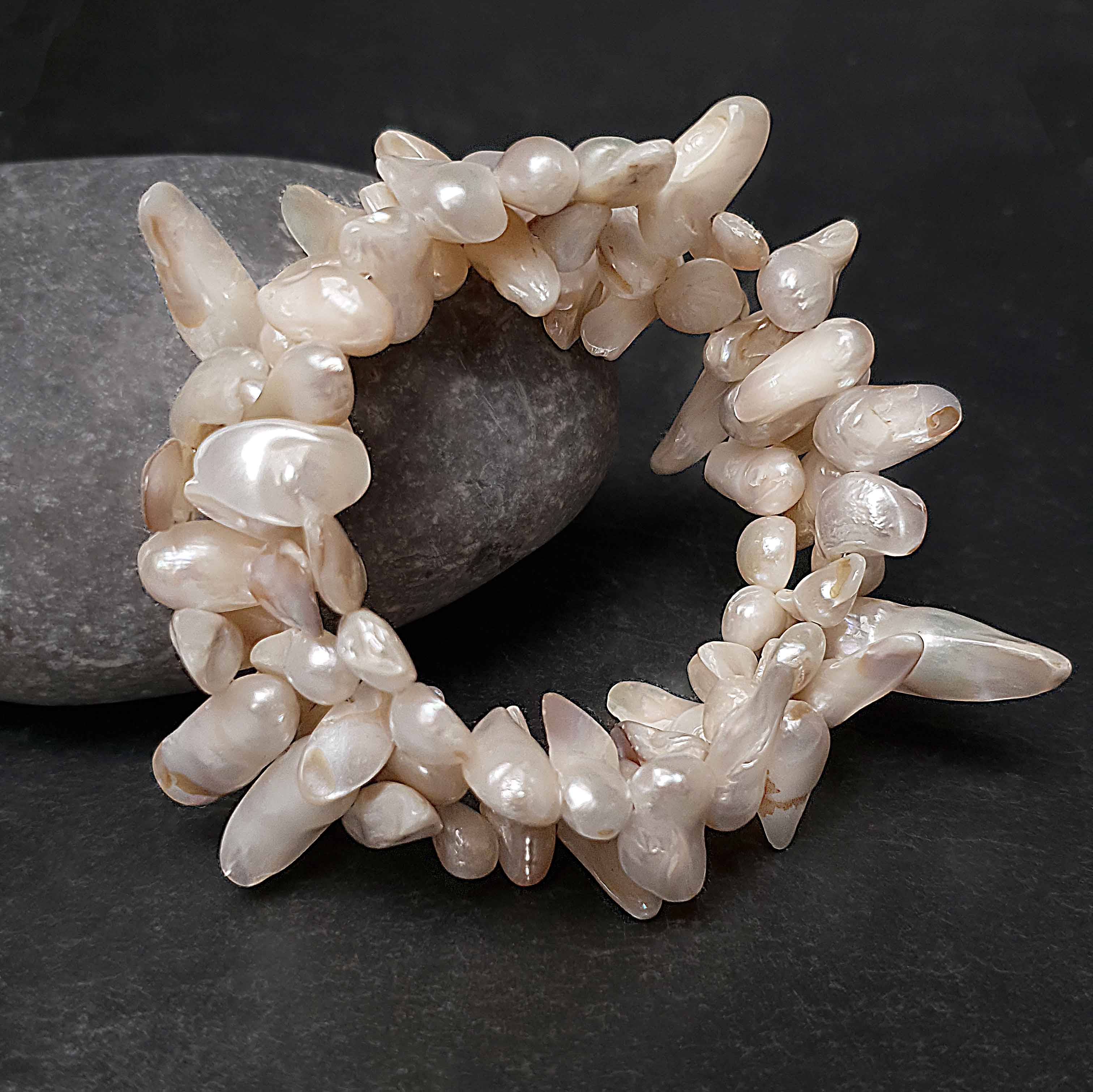 Wit zoetwater parel wikkel armband liggend tegen kei | Winky