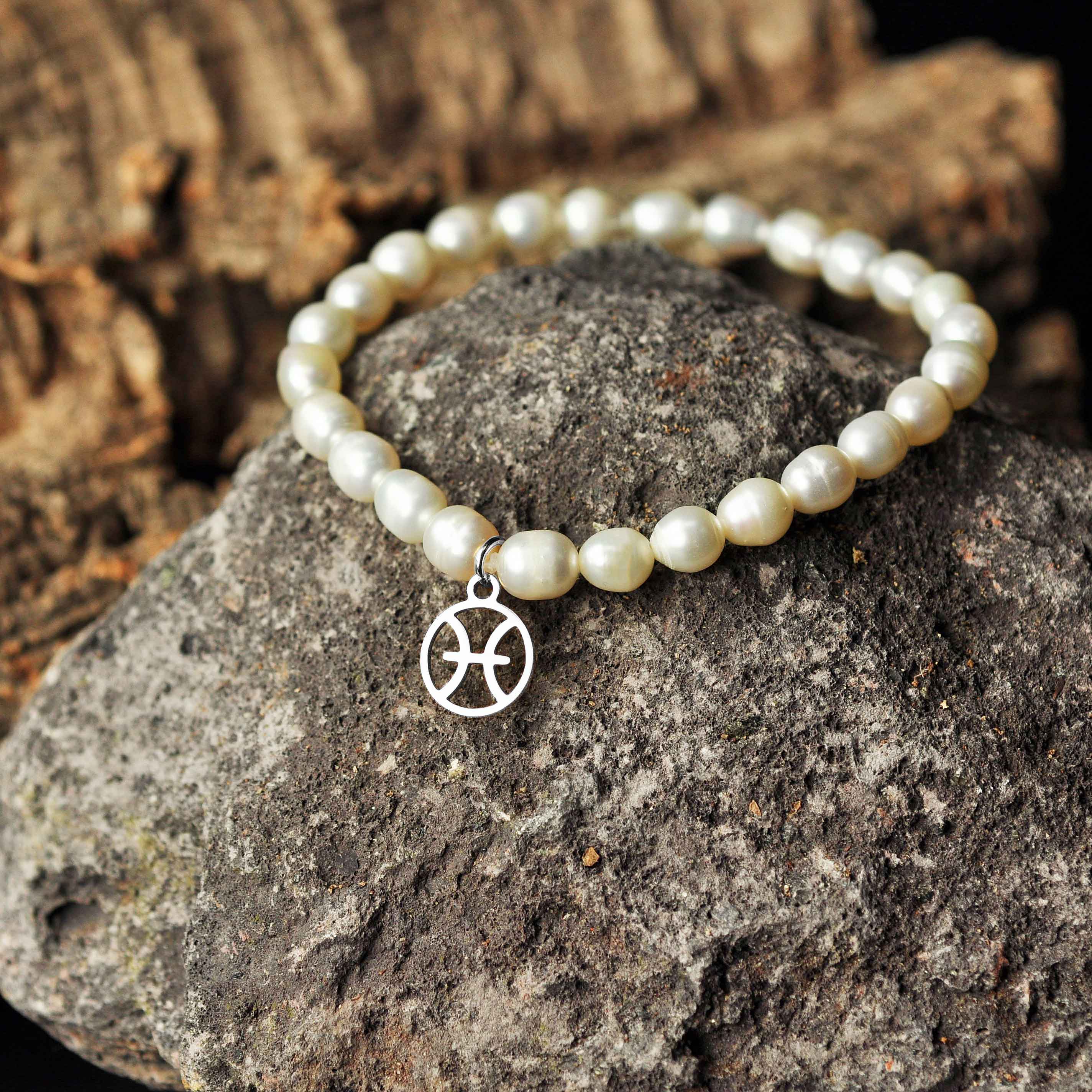 Wit zoetwater parel armband met zilver edelstalen symbool van sterrenbeeld Vissen liggend op zwarte steen | Parel armband Zilveren Sterrenbeeld Vissen