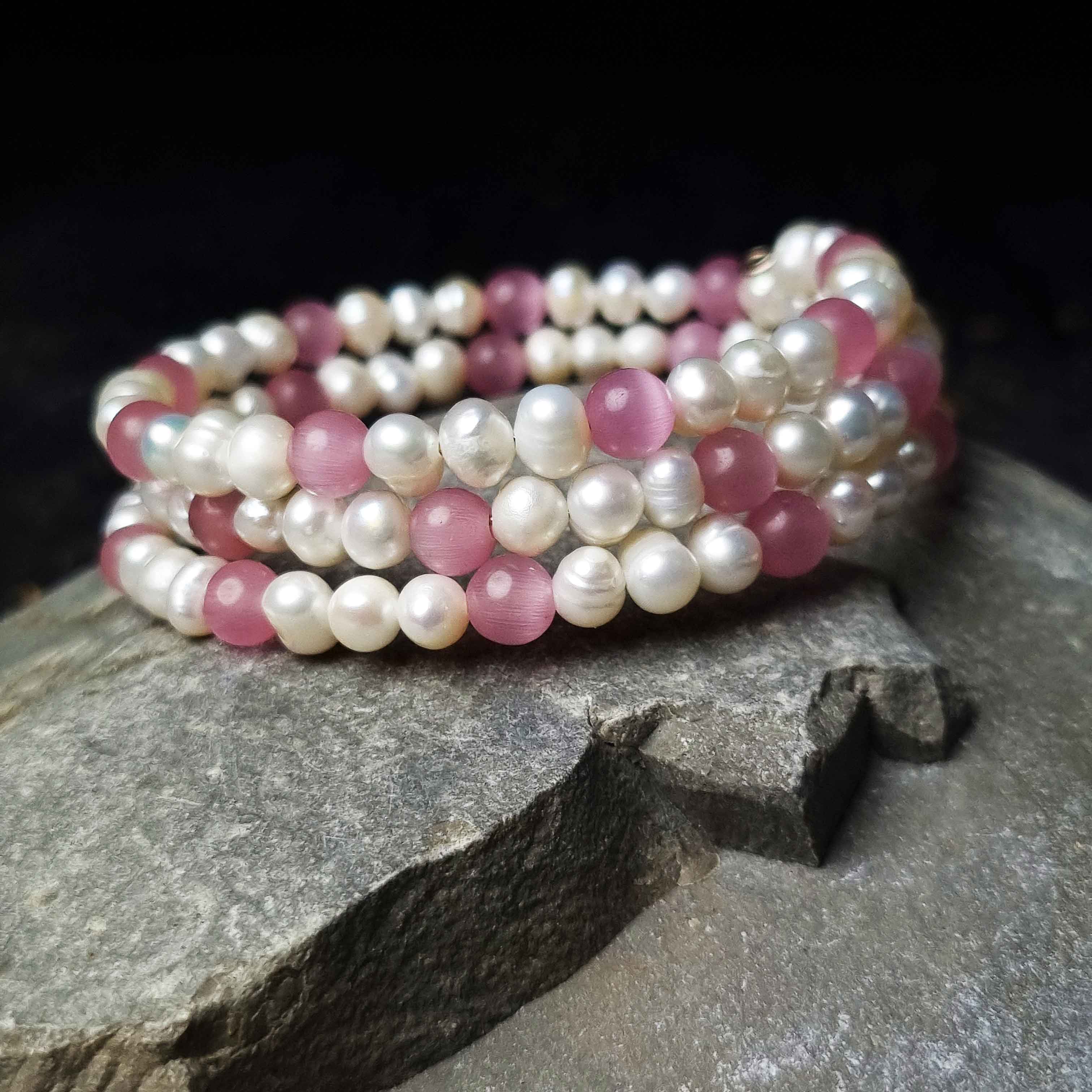 Wit zoetwater parel wikkelarmband met roze edelsteen kattenoog liggend op kei | Pearl Pink Cat&