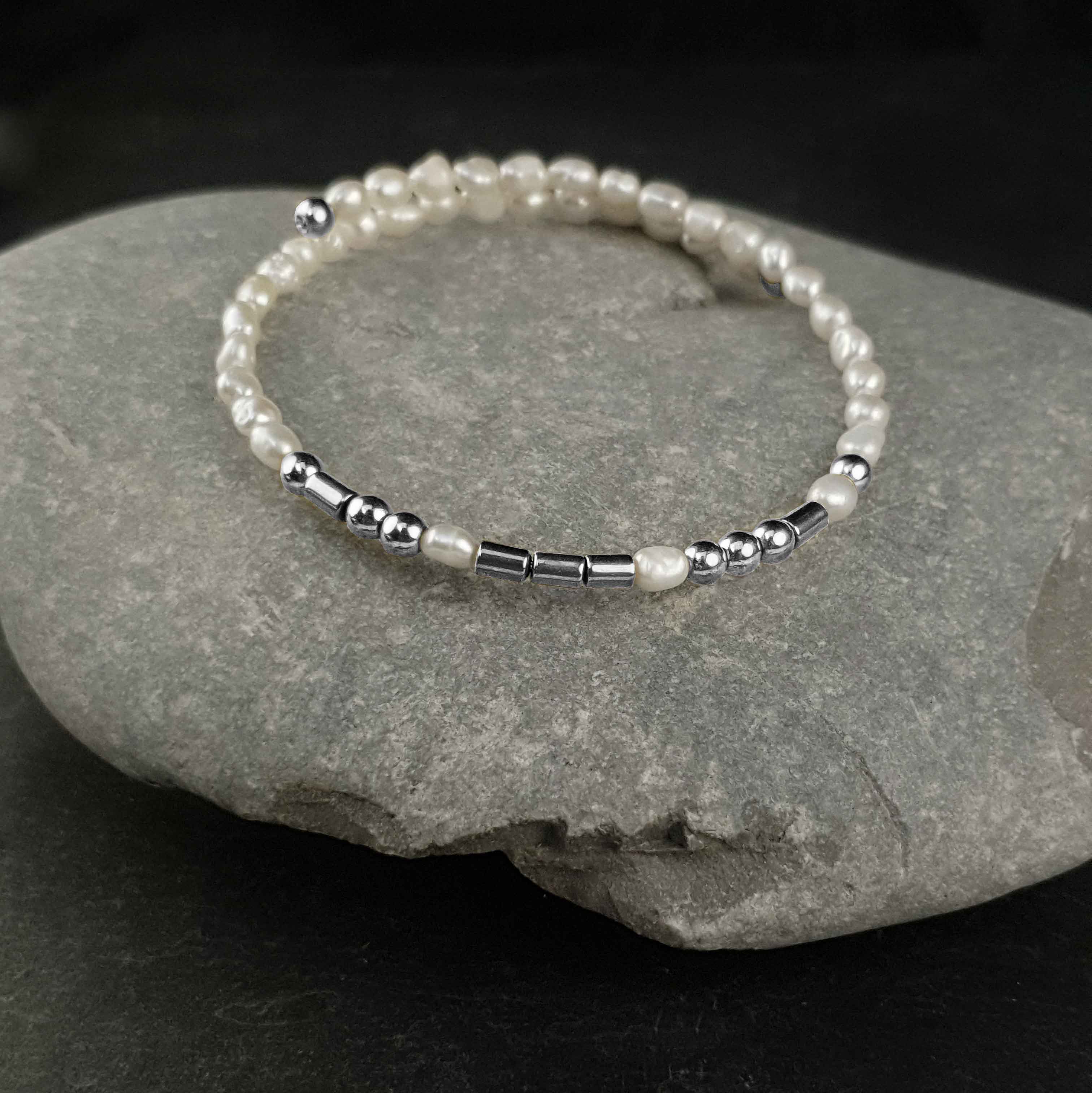 Wit zoetwater parel wikkelarmband met verborgen boodschap in Morse code met edelsteen zilver hematiet liggend op kei | Cadeau set zoetwater parel armband Morse Code LOVE Pearl Silver