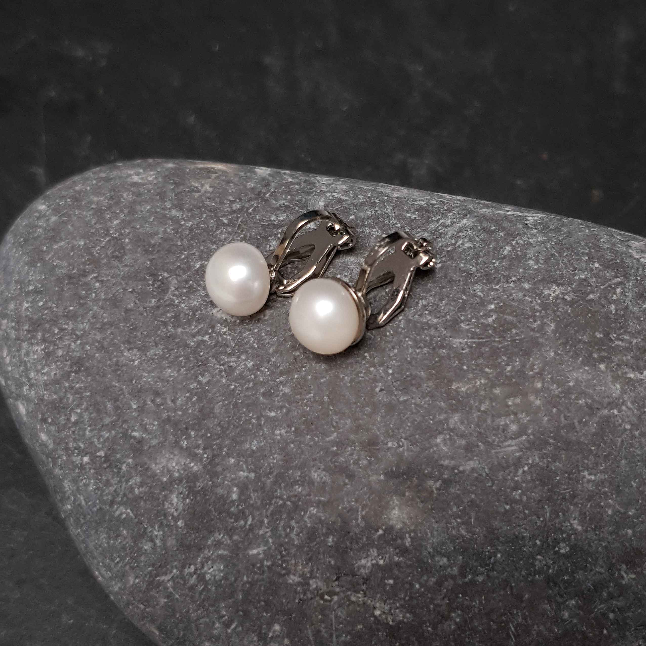 Witte zoetwater parel oorbellen met clip, clip oorbellen met parel liggend op steen, zijaanzicht | Clip Pearl