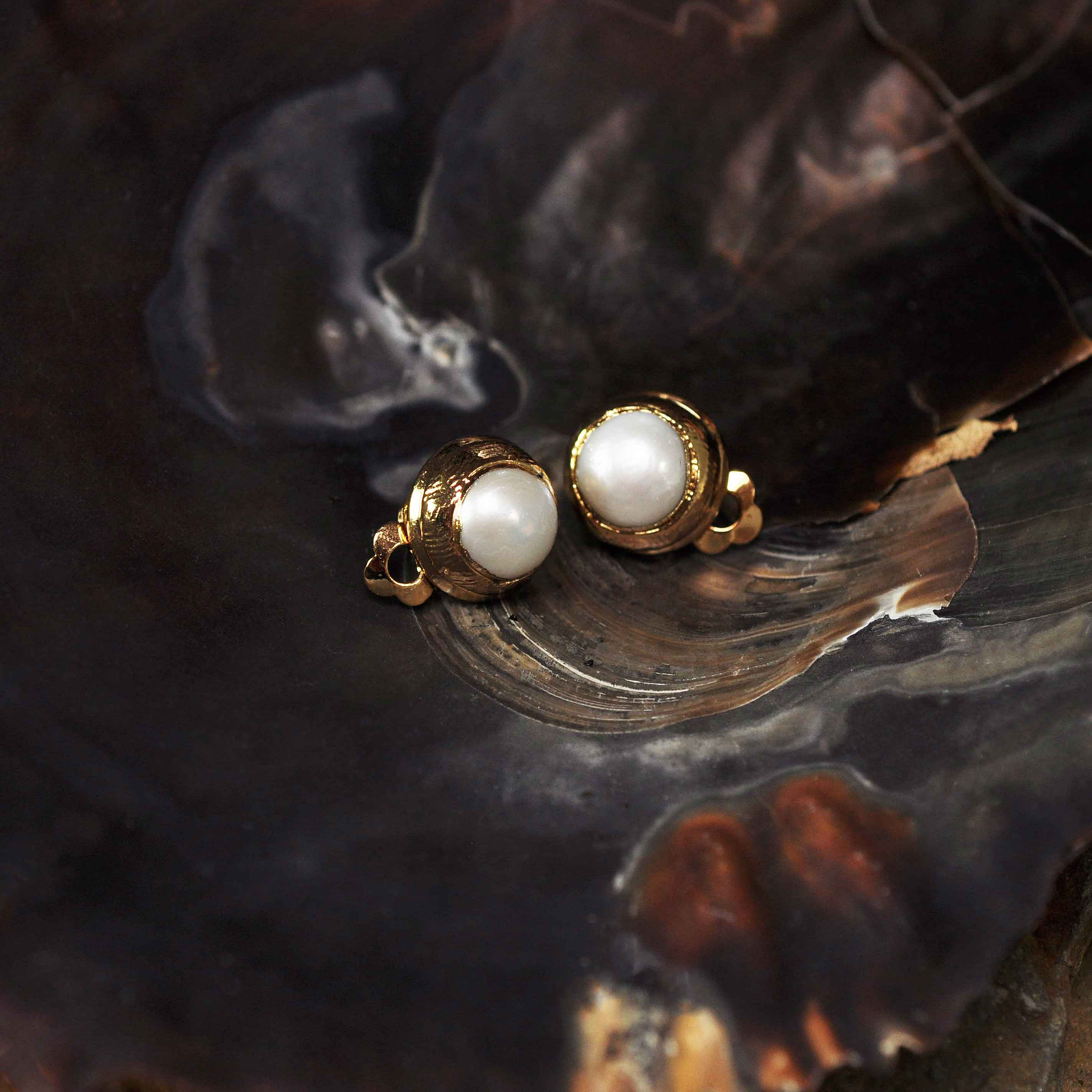 Witte zoetwater parel clips oorbellen met gouden rand liggend in schelp | One Gold Clip Pearl