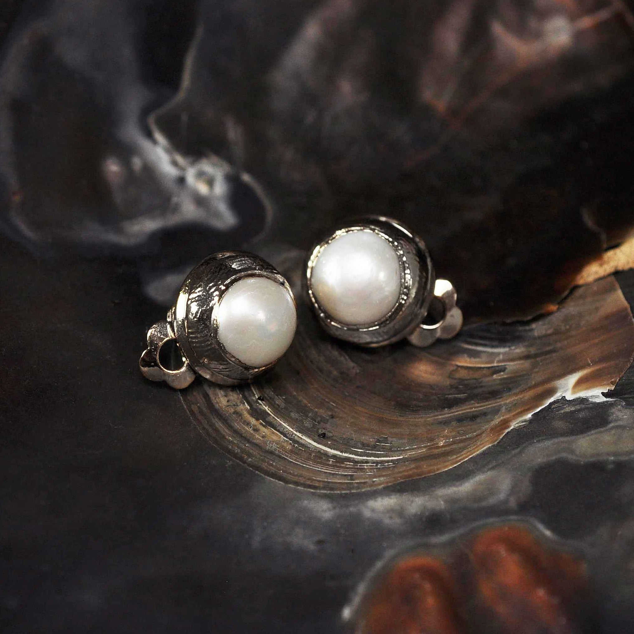 Witte zoetwater parel clips oorbellen met zilveren rand liggend in schelp | One Silver Clip Pearl