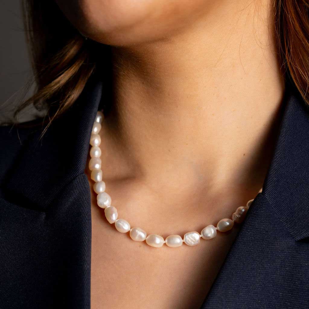Handgeknoopte zoetwater parelketting met witte parels op model met blauw jasje | Wola