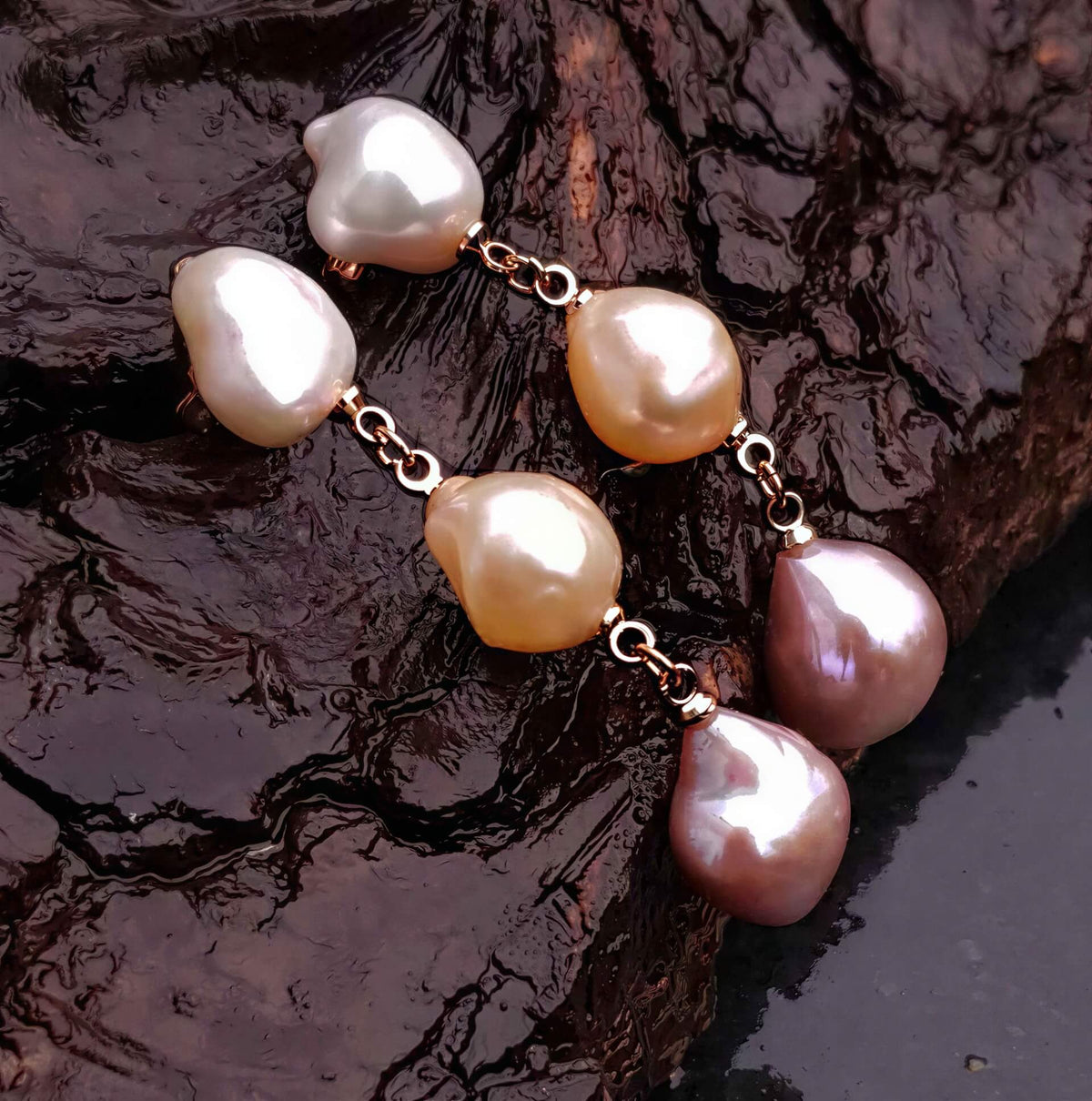 Lange zoetwater parel oorbellen met witte, zalm en roze barok parels en rosé goud hangend aan natte schors, zijaanzicht | 3 Baroque Soft Pearls