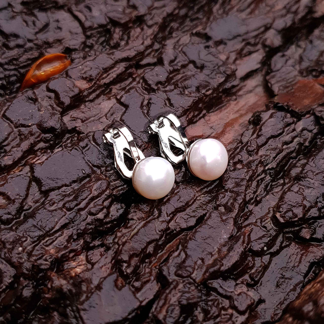 Witte zoetwater parel oorbellen met clip, clip oorbellen met parel liggend op schors | Clip Pearl