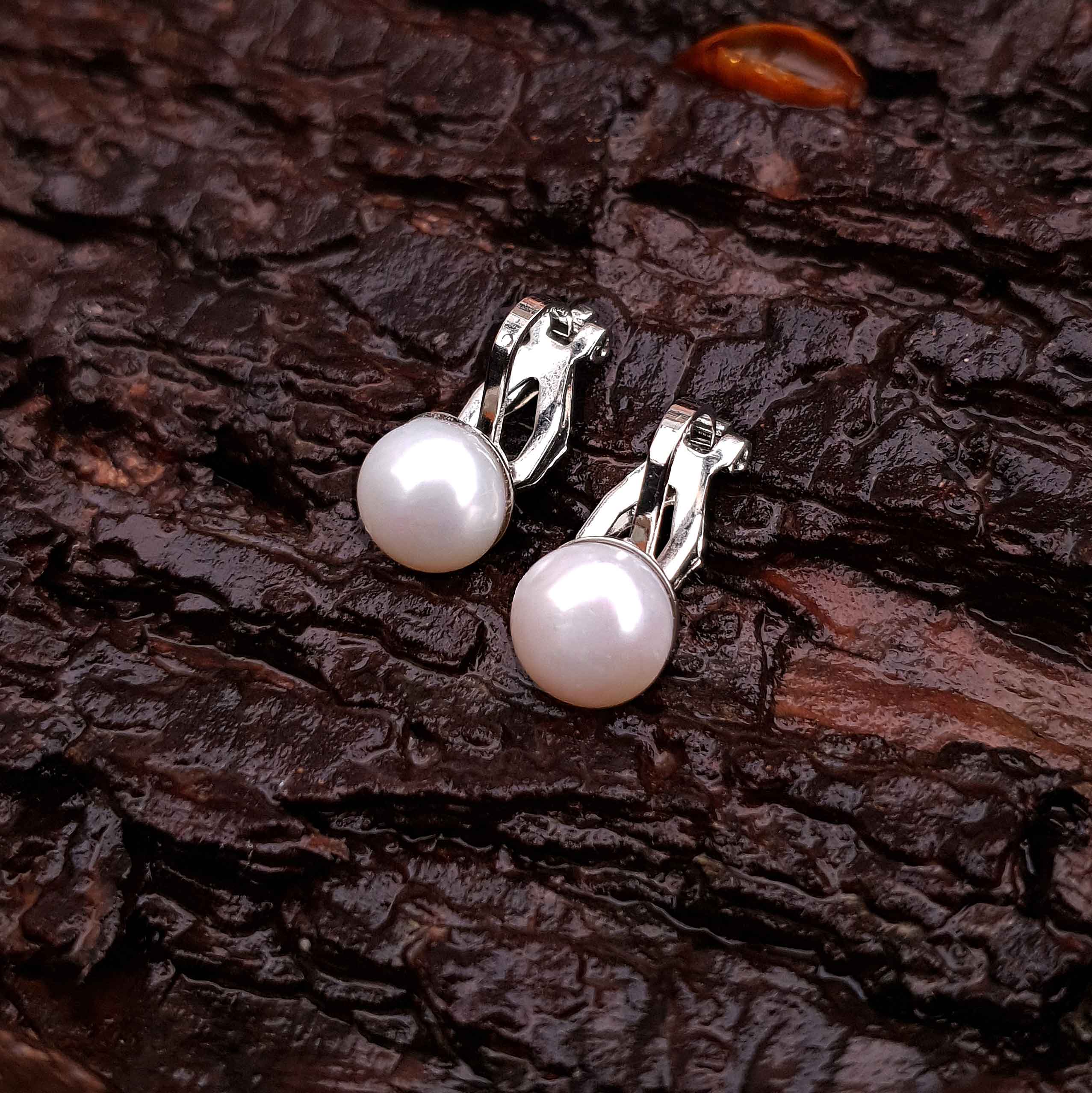 Witte zoetwater parel oorbellen met clip, clip oorbellen met parel liggend op schors, bovenaanzicht | Clip Pearl