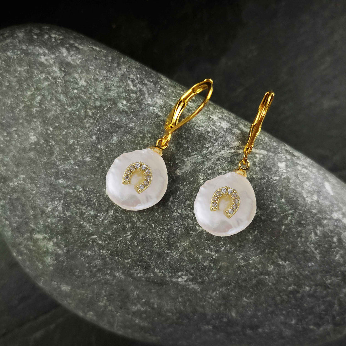 Witte zoetwater parel oorbellen met goud edelstaal en parel hanger is voorzien van stras steentjes in een hoefijzer liggend op steen | Coin Pearl Good Luck