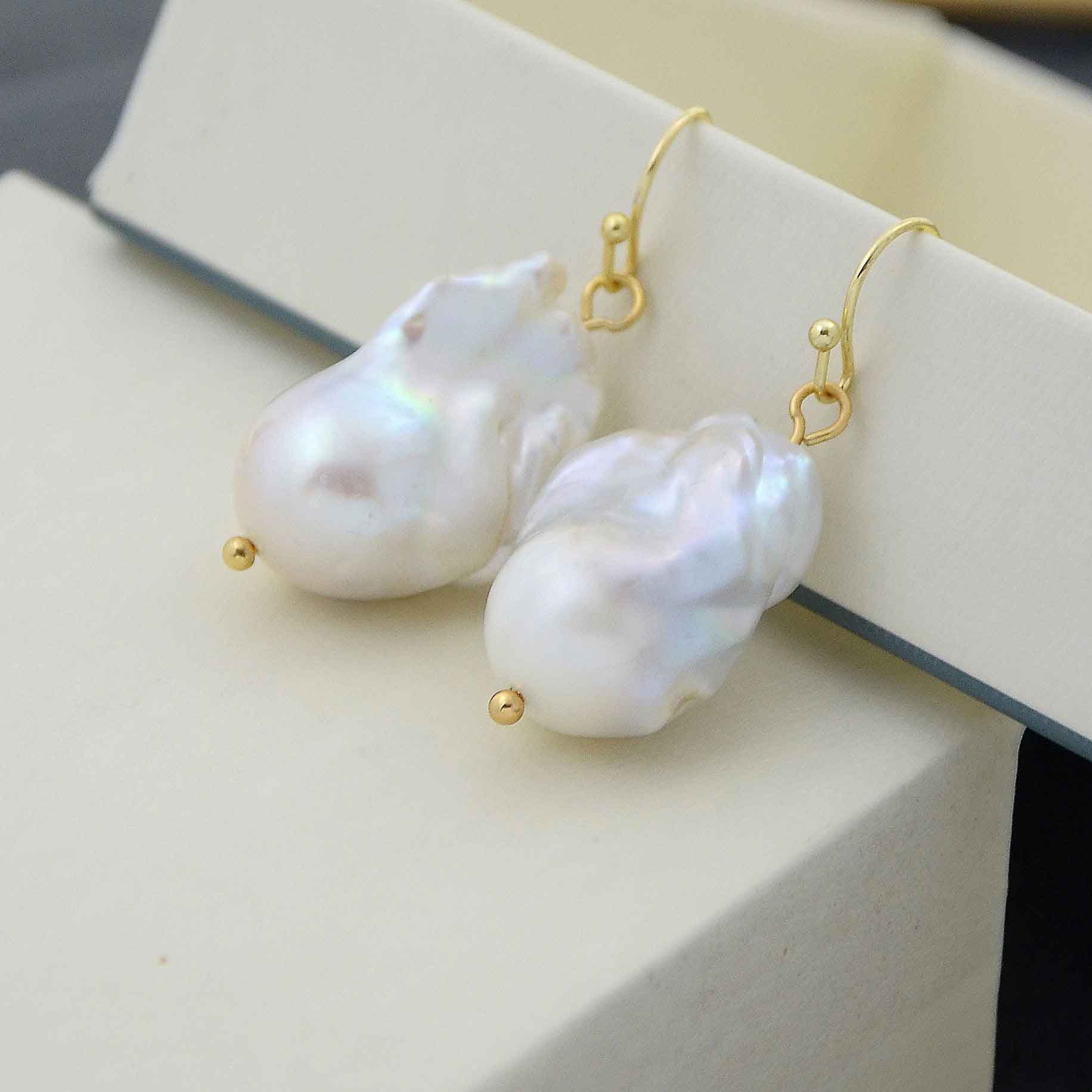 Grote witte zoetwater parel oorbellen met goud edelstaal liggend op doosje | parel oorbellen Ebalien