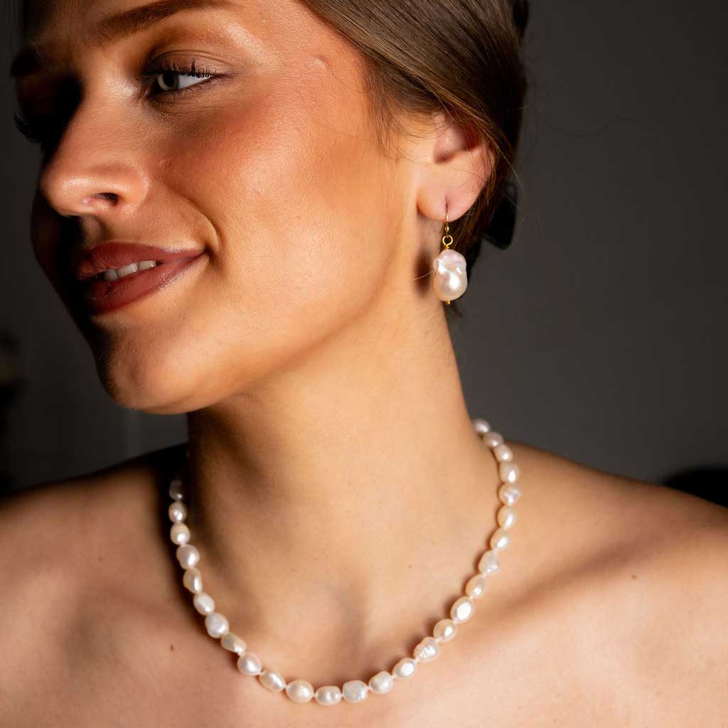 Grote witte zoetwater parel oorbellen met goud edelstaal op model detail | parel oorbellen Ebalien