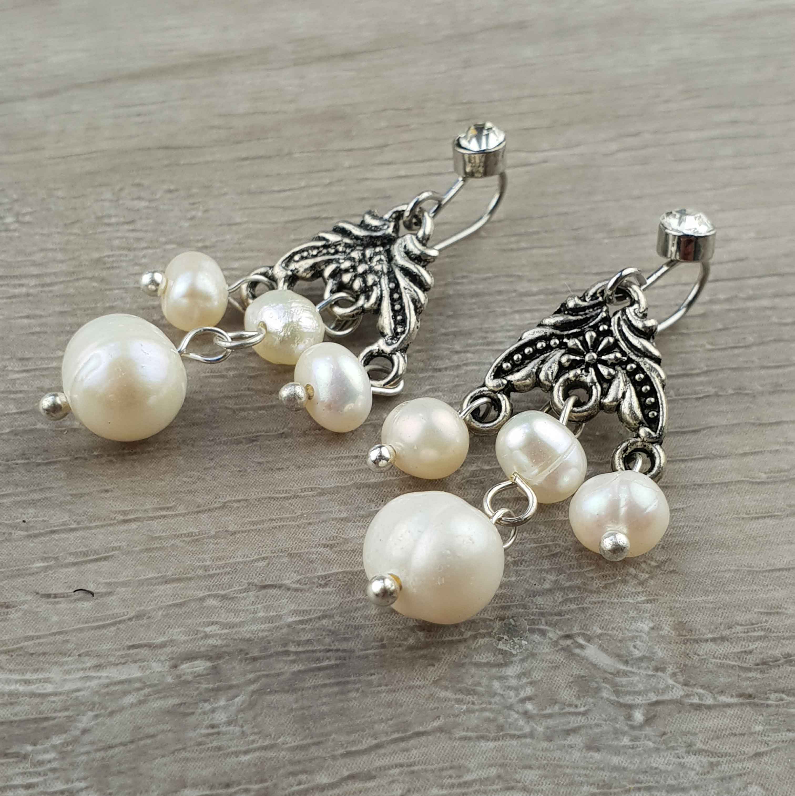 Witte zoetwater parel oorbellen met stras steentje liggend op hout | Emmy