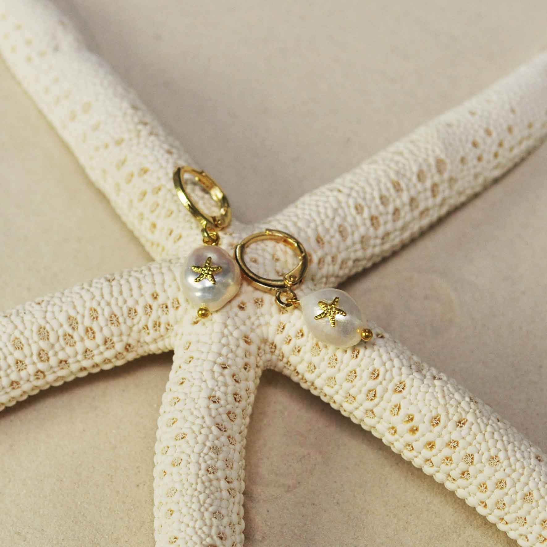 Witte zoetwater parel oorbellen met gouden zeester met oorringen liggend op het strand | Gold Pearl Starfish