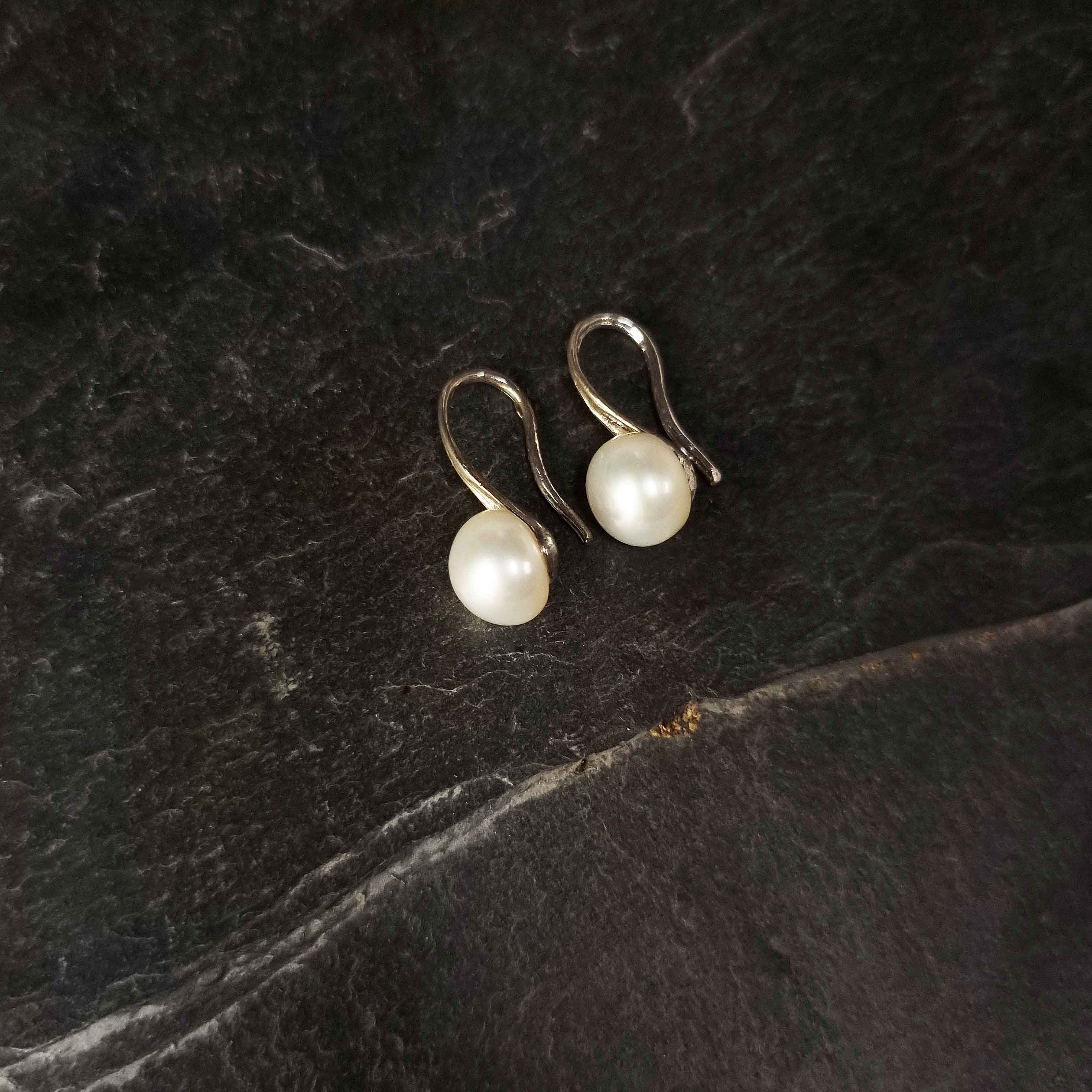 Witte zoetwater parel oorbellen liggend op leisteen | Leis White