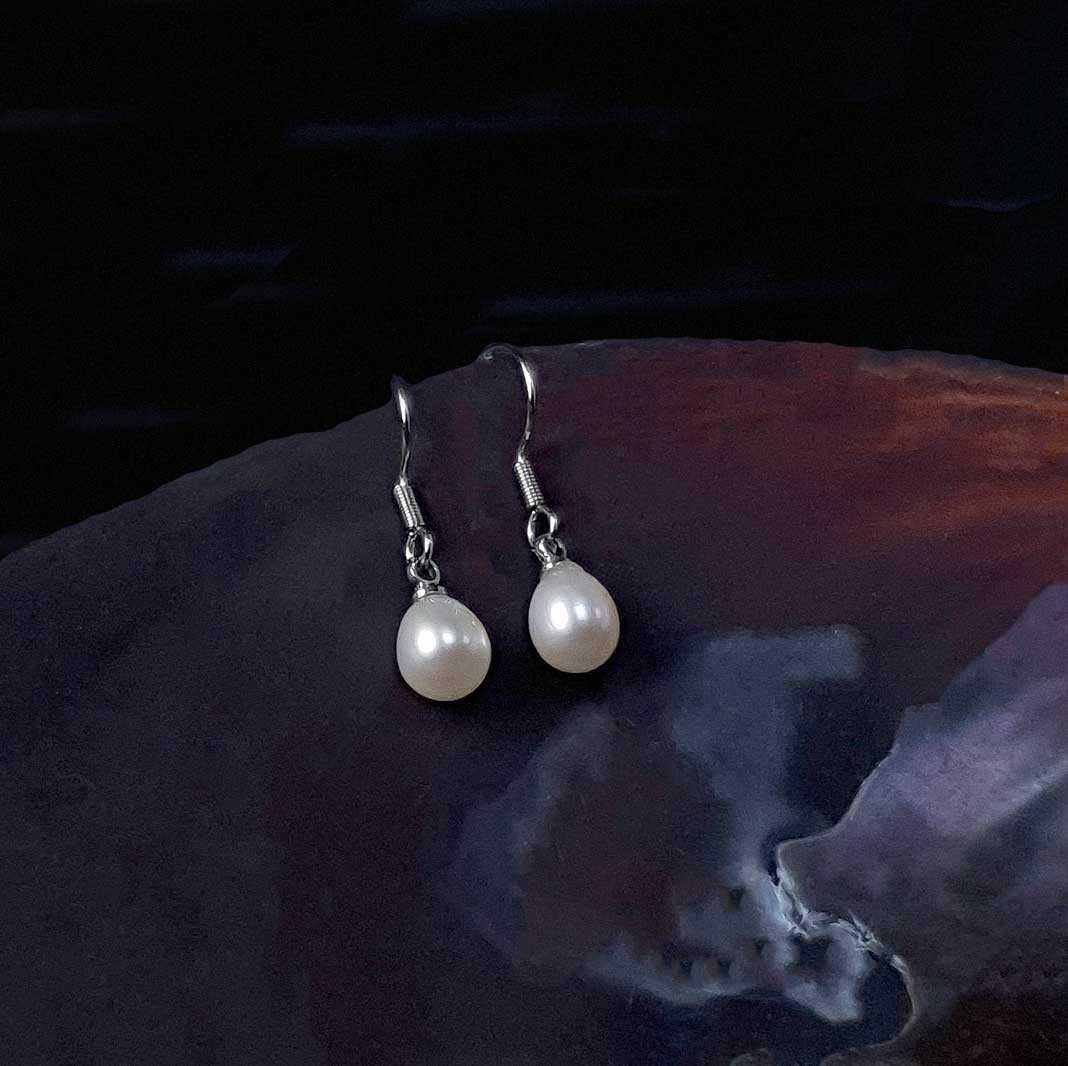 Witte zoetwater parel oorbellen met sterling zilveren oorbelhaakjes liggend in schelp | Lianca