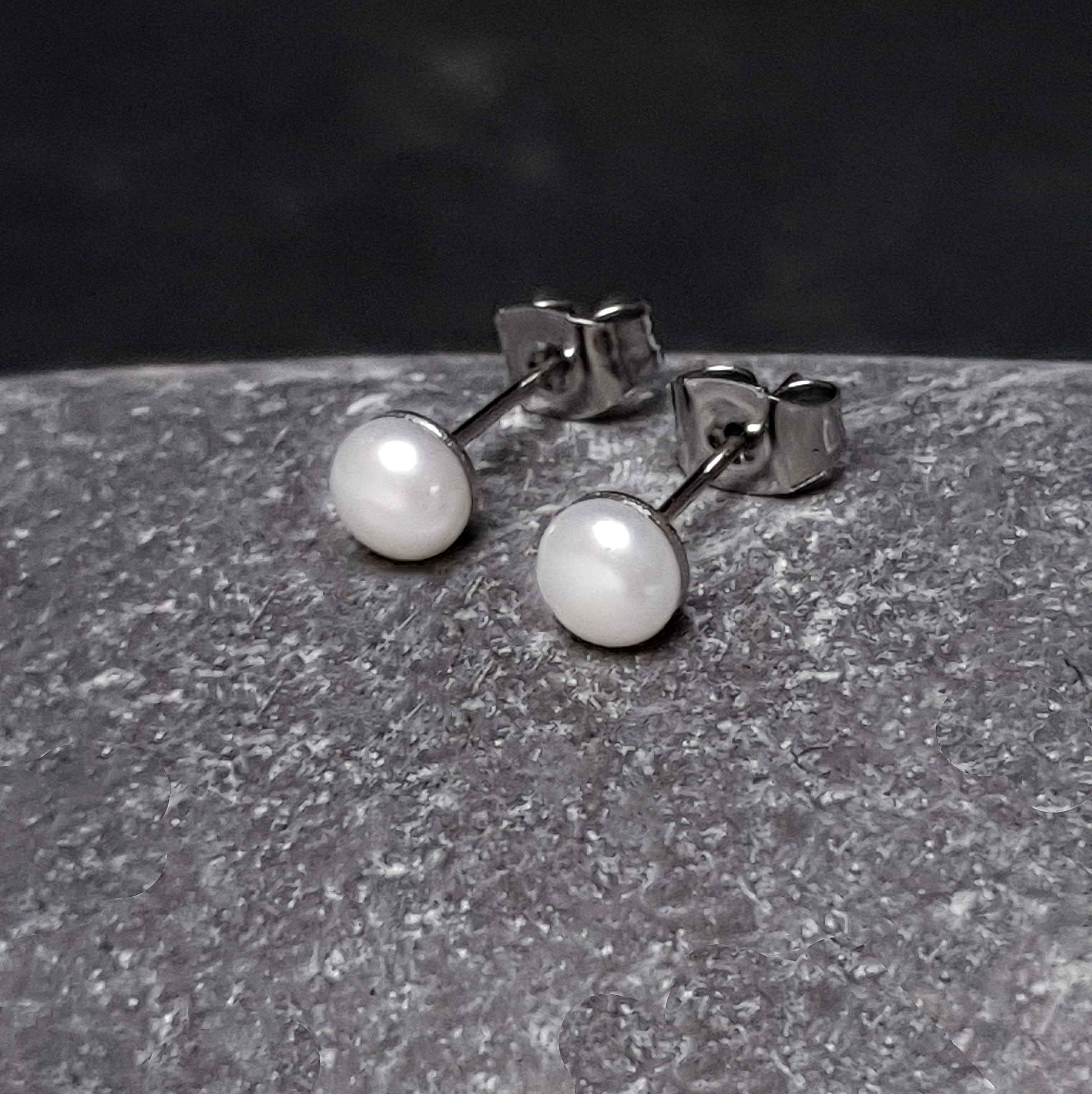 Witte zoetwater parel oorbellen met edelstaal liggend op kei | Little Pearl