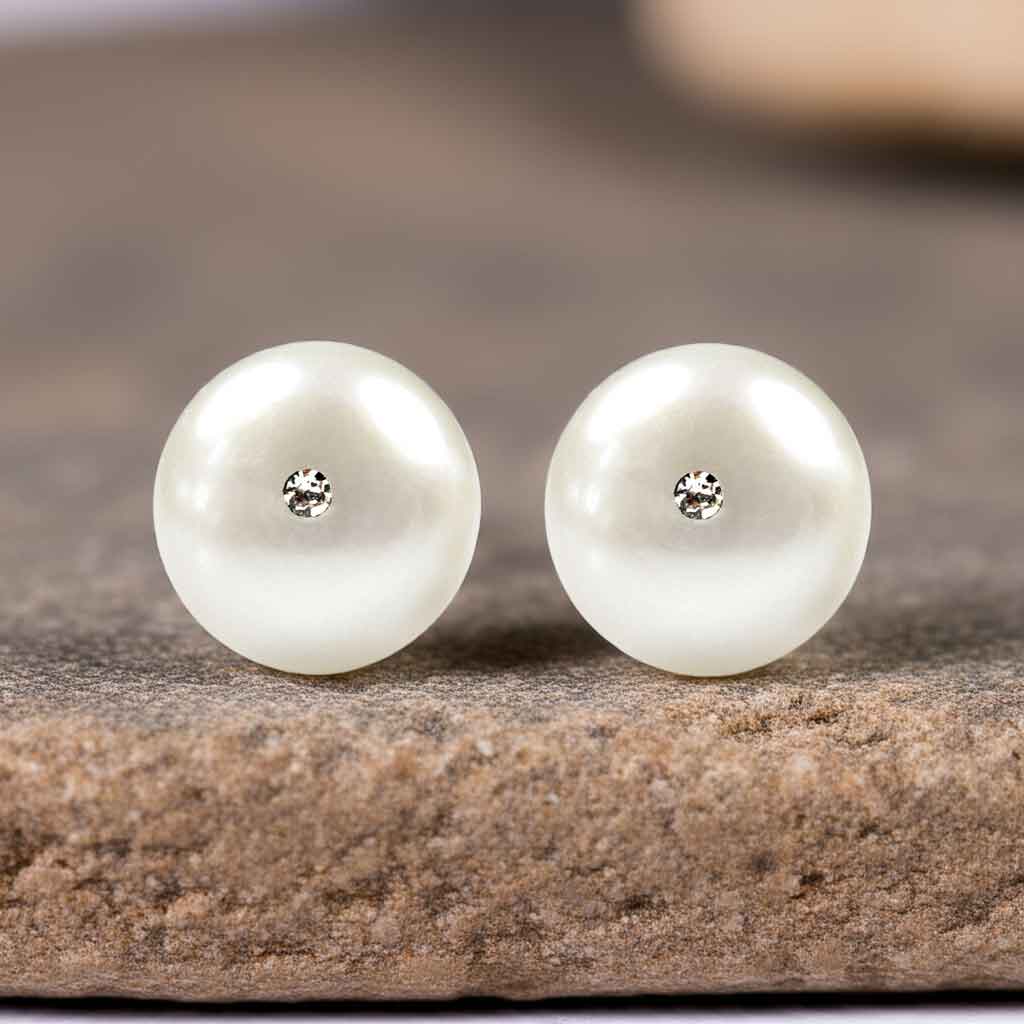 Witte zoetwater parel oorbellen met stras steentje liggend op beige steen vooraanzicht | Zoetwater parel oorbellen Bling Mea W
