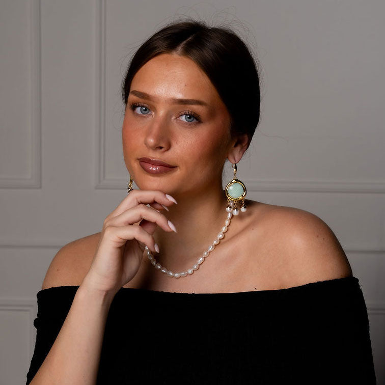 Witte zoetwater parel oorbellen met groene edelsteen amazoniet en goud edelstaal met model aan tafel | Editha Green