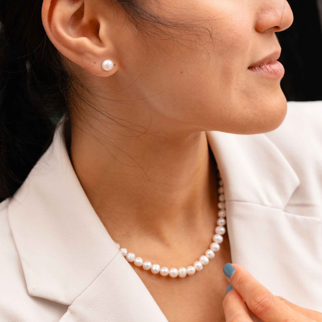 Zoetwater parel set bestaande uit een parelketting en parel oorbellen met witte parels en sterling zilver (925) op model met wit jasje zijaanzicht | set Bella (KO)