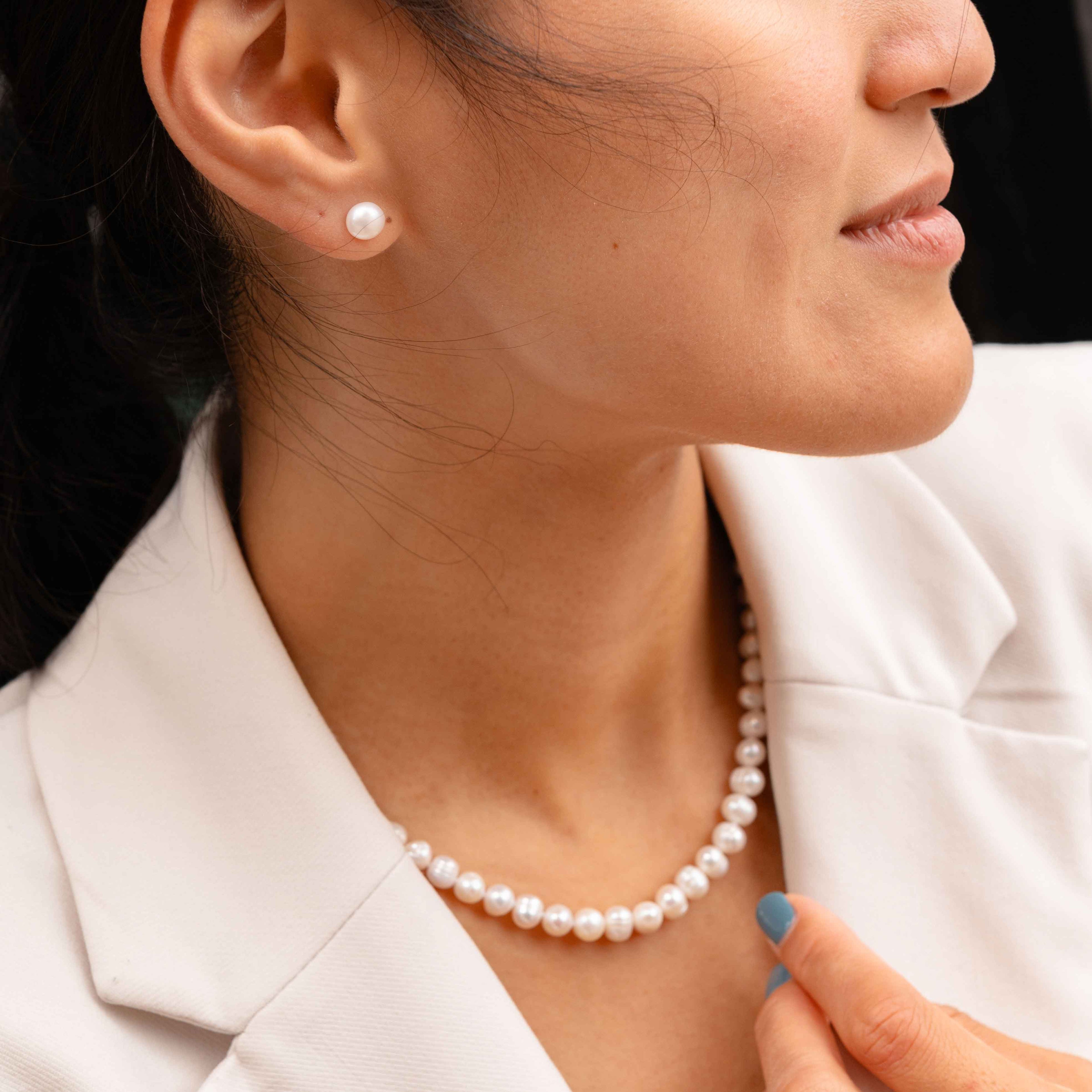 Zoetwater parel set bestaande uit een parelketting en parel oorbellen met witte parels en sterling zilver (925) op model met wit jasje zijaanzicht | set Bella (KO)