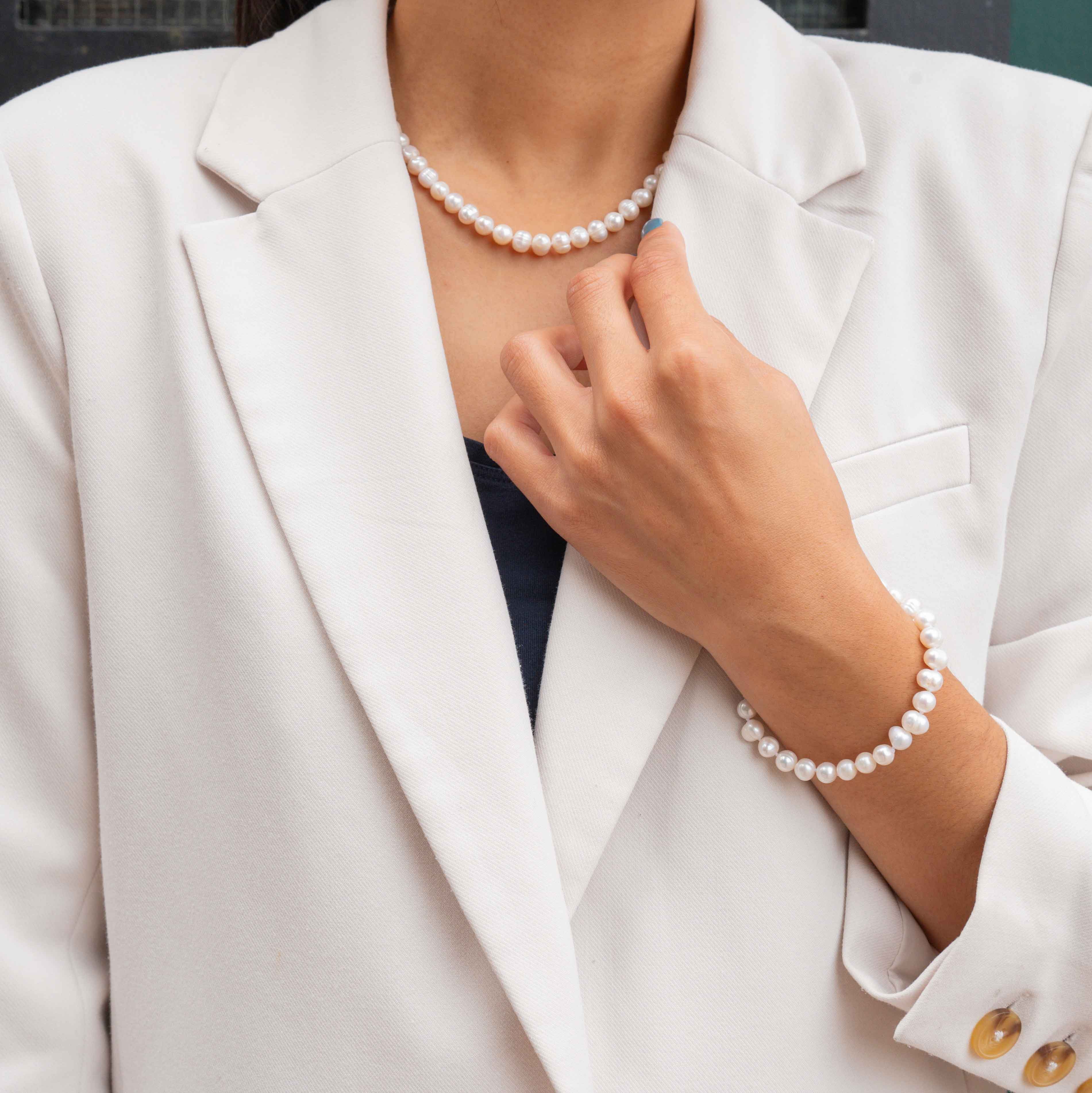 Witte zoetwater parel set met sterling zilveren slotjes bestaande uit een witte parelketting en witte parel armband op model met wit jasje | set Bella (KA)
