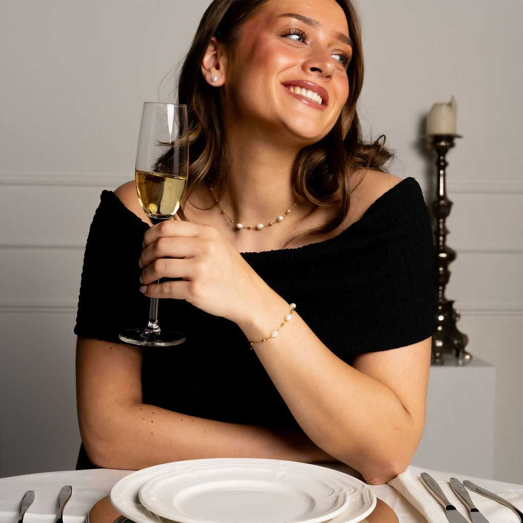 Witte zoetwater parelketting met goud edelstaal met model aan tafel | Parelketting Eline Goud
