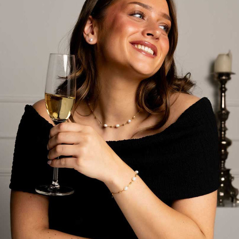 Witte zoetwater parelketting met goud edelstaal met model aan tafel | Parelketting Eline Goud