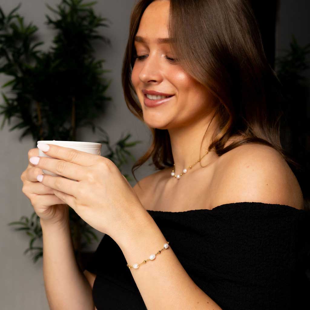 Witte zoetwater parelketting met goud edelstaal met model drinkt thee | Parelketting Eline Goud