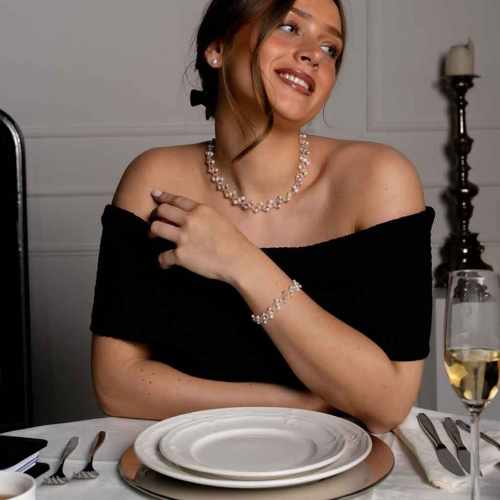 Zoetwater parel set bestaande uit een parelketting en parel armband met witte, zalm en roze parels en magneetslot op model aan tafel | set Felicia