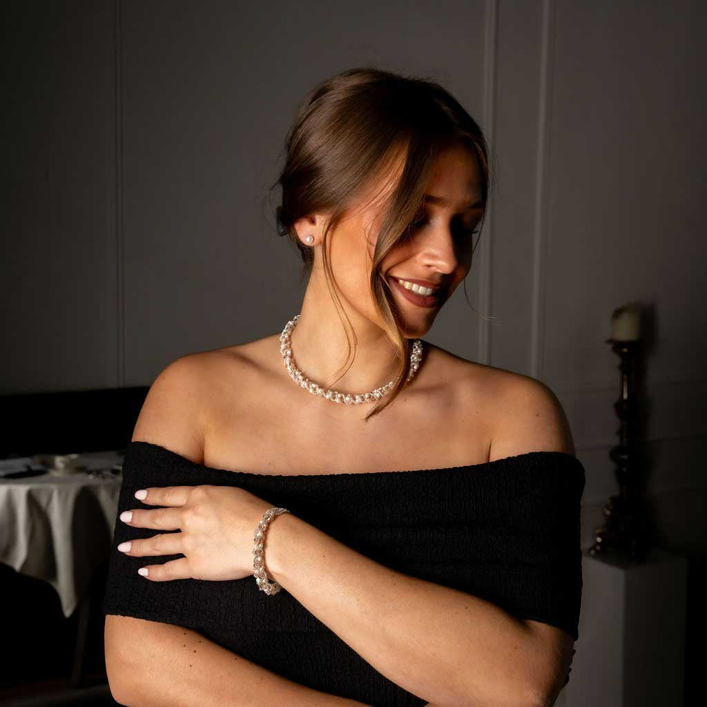 Witte zoetwater parel set bestaande uit een parelketting en parel armband met beige glaskristallen op model met zwarte jurk | set Pearl Crystal Clear