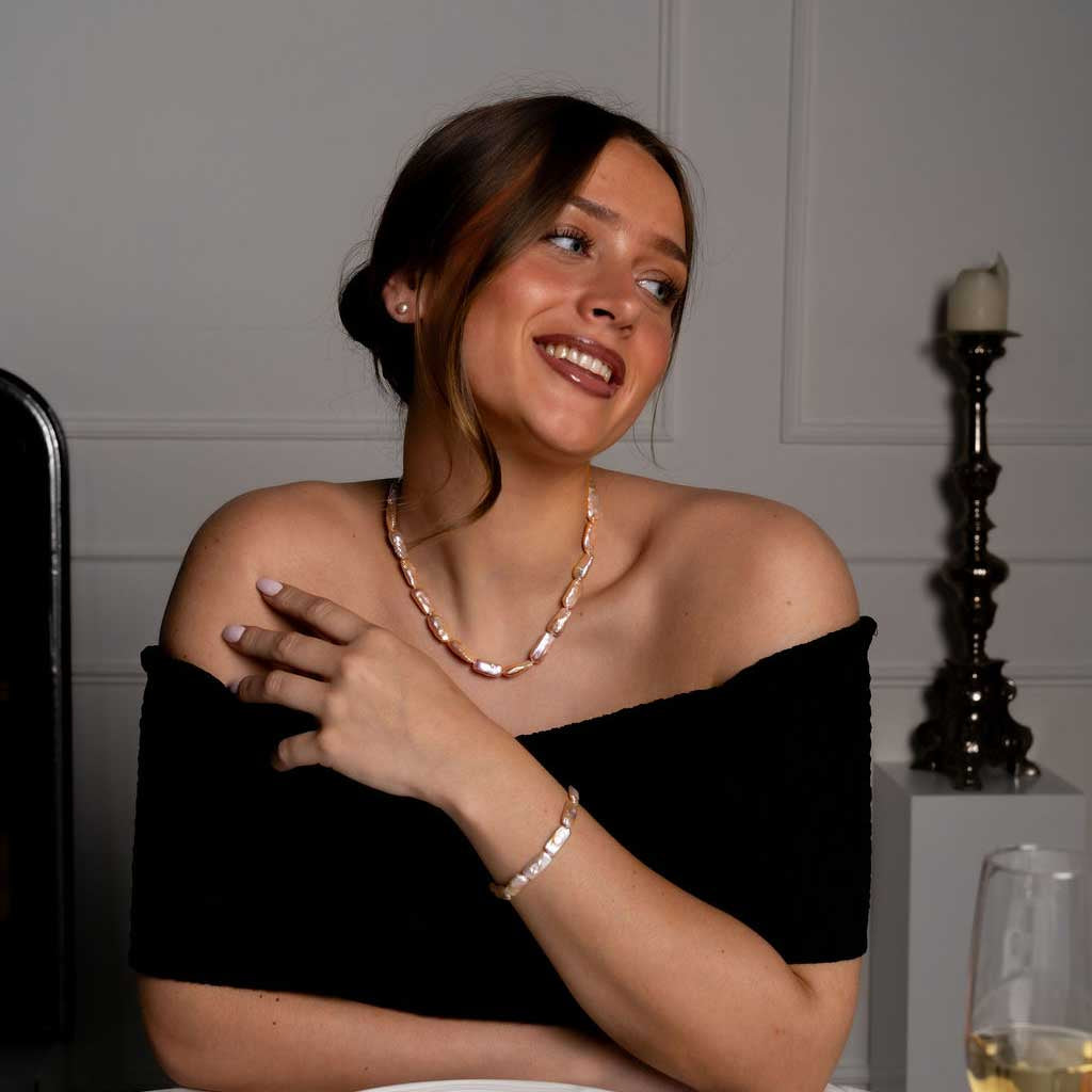 Handgeknoopte zoetwater parel set bestaande uit parelketting en parel armband met zalm kleurige rechthoekige parels en sterling zilver (925) op model aan tafel | set Pearl Rectangle Peach