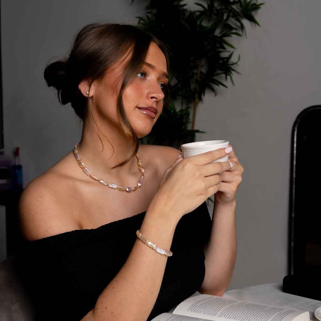 Handgeknoopte zoetwater parel set bestaande uit parelketting en parel armband met zalm kleurige rechthoekige parels en sterling zilver (925) op model met boek | set Pearl Rectangle Peach
