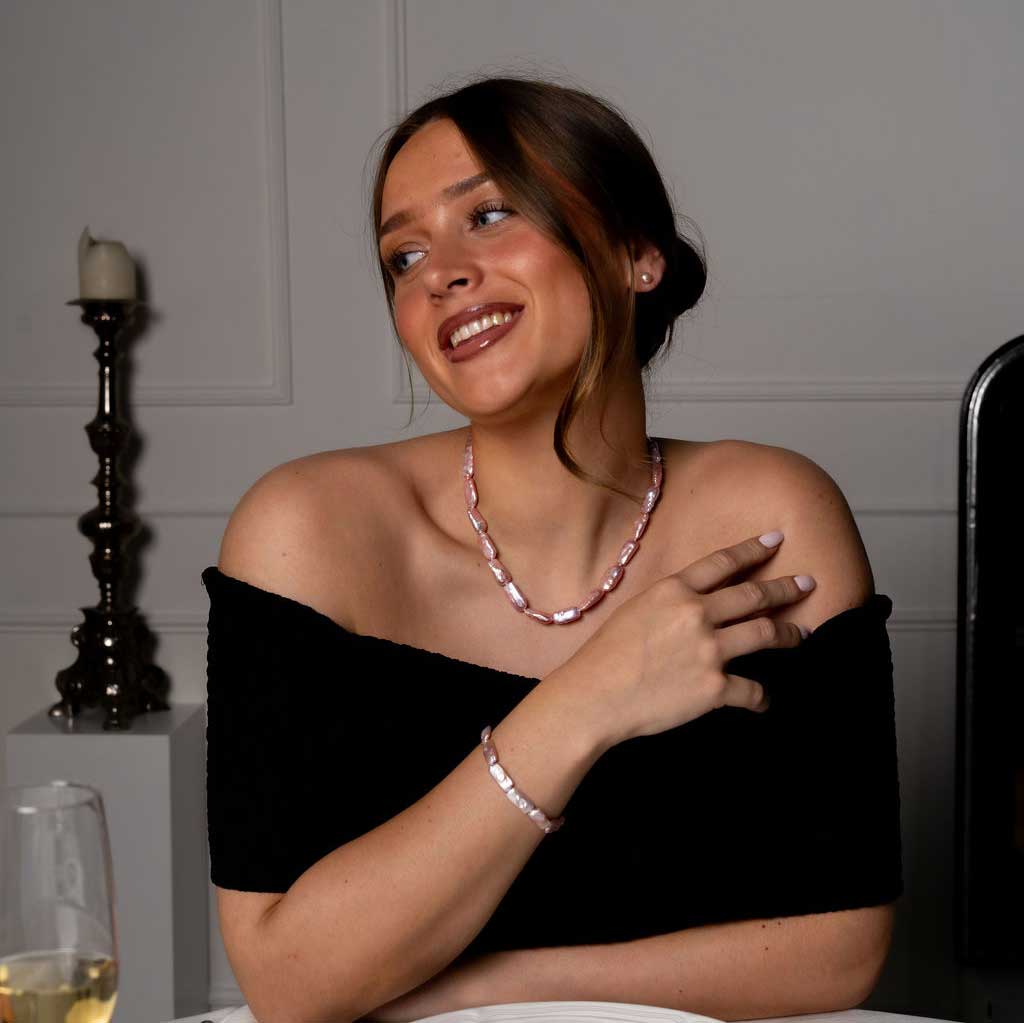 Handgeknoopte zoetwater parel set bestaande uit parelketting en parel armband met roze rechthoekige parels en sterling zilver (925) op model aan tafel | set Pearl Rectangle Pink