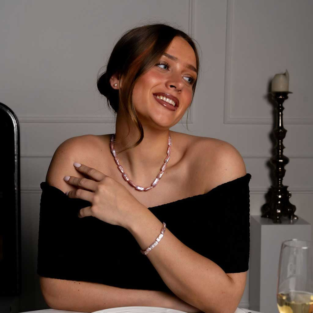 Handgeknoopte zoetwater parel set bestaande uit parelketting en parel armband met roze rechthoekige parels en sterling zilver (925) op model aan tafel | set Pearl Rectangle Pink