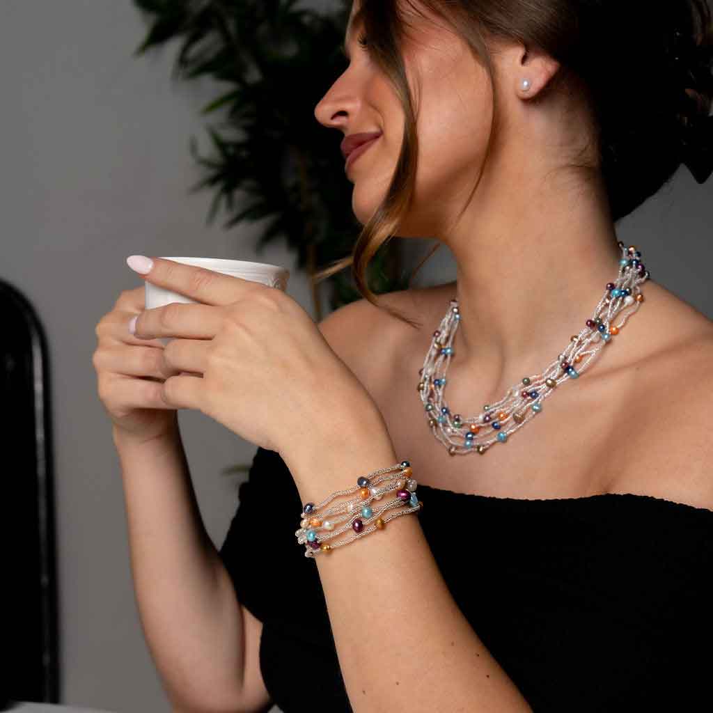 Zoetwater parel set met parelketting en parel armband met 7 strengen bontgekleurde parels en zilveren glaskraaltjes met magneetslot met model drinkt koffie | set Viva