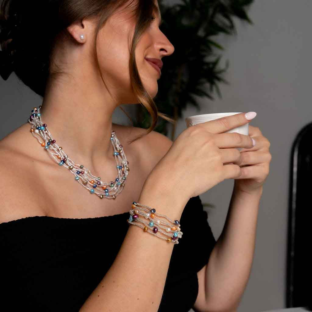 Zoetwater parel set met parelketting en parel armband met 7 strengen bontgekleurde parels en zilveren glaskraaltjes met magneetslot met model drinkt koffie | set Viva