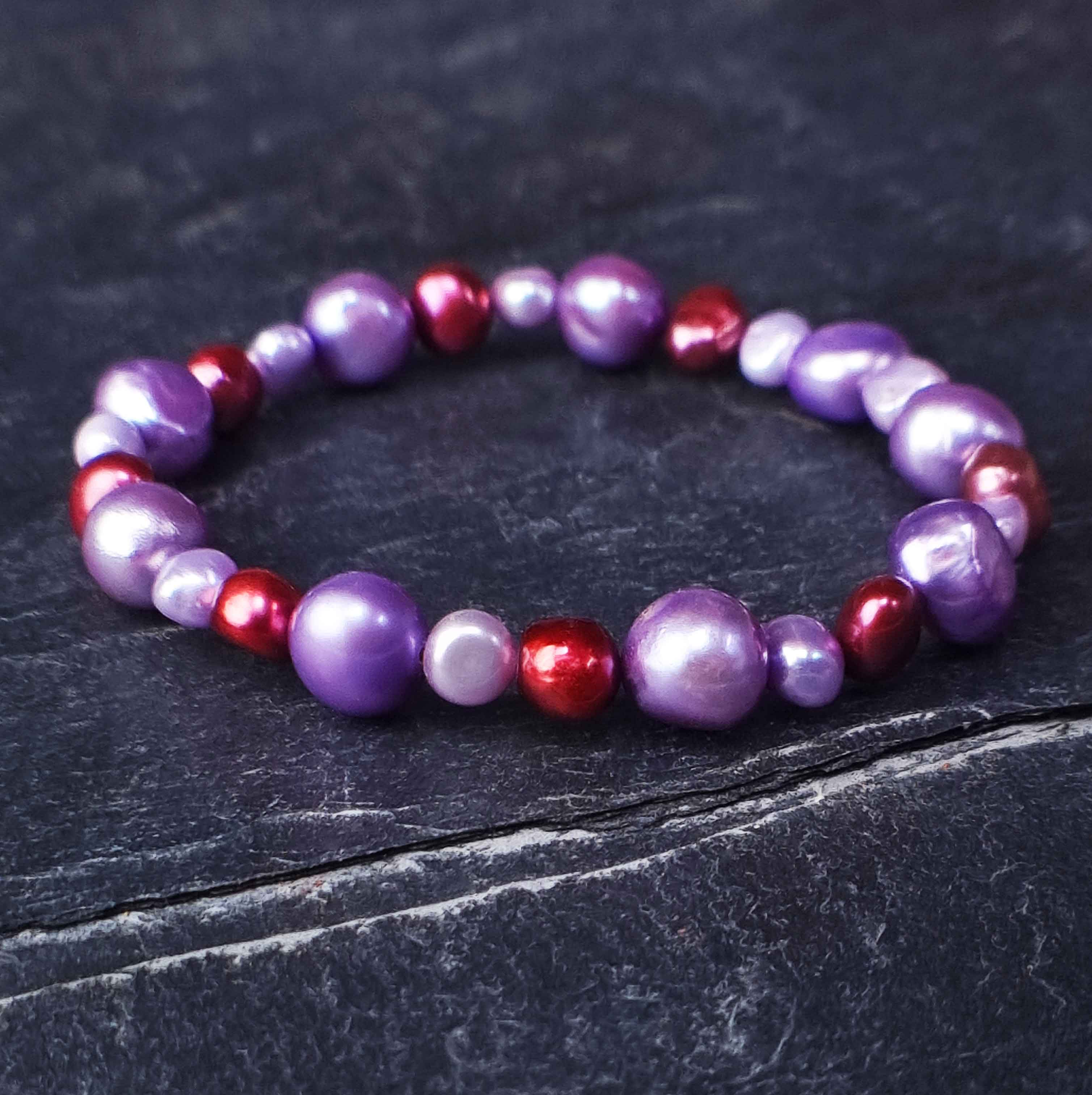 Zoetwater parel armband met lila en rode parels liggend op leisteen | Pulla