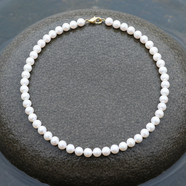 Witte zoetwater parelketting met goud edelstalen slotje liggend op steen in water | Bella Gold
