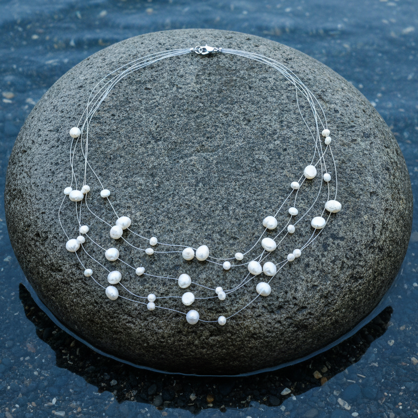 Zoetwater parelketting met witte parels in 5 rijen en sterling zilver (925) liggend op steen in water | Gill W