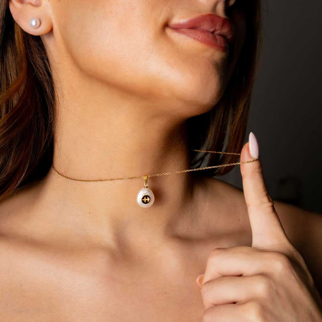 Detail van zoetwater parelketting met witte parel hanger met gouden symbool van sterrenbeeld boogschutter en goud edelstaal om hals | Gouden Sterrenbeeld Boogschutter