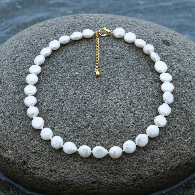 Witte zoetwater parelketting met coin parels en goud edelstaal liggend op steen | Little Coin Pearl